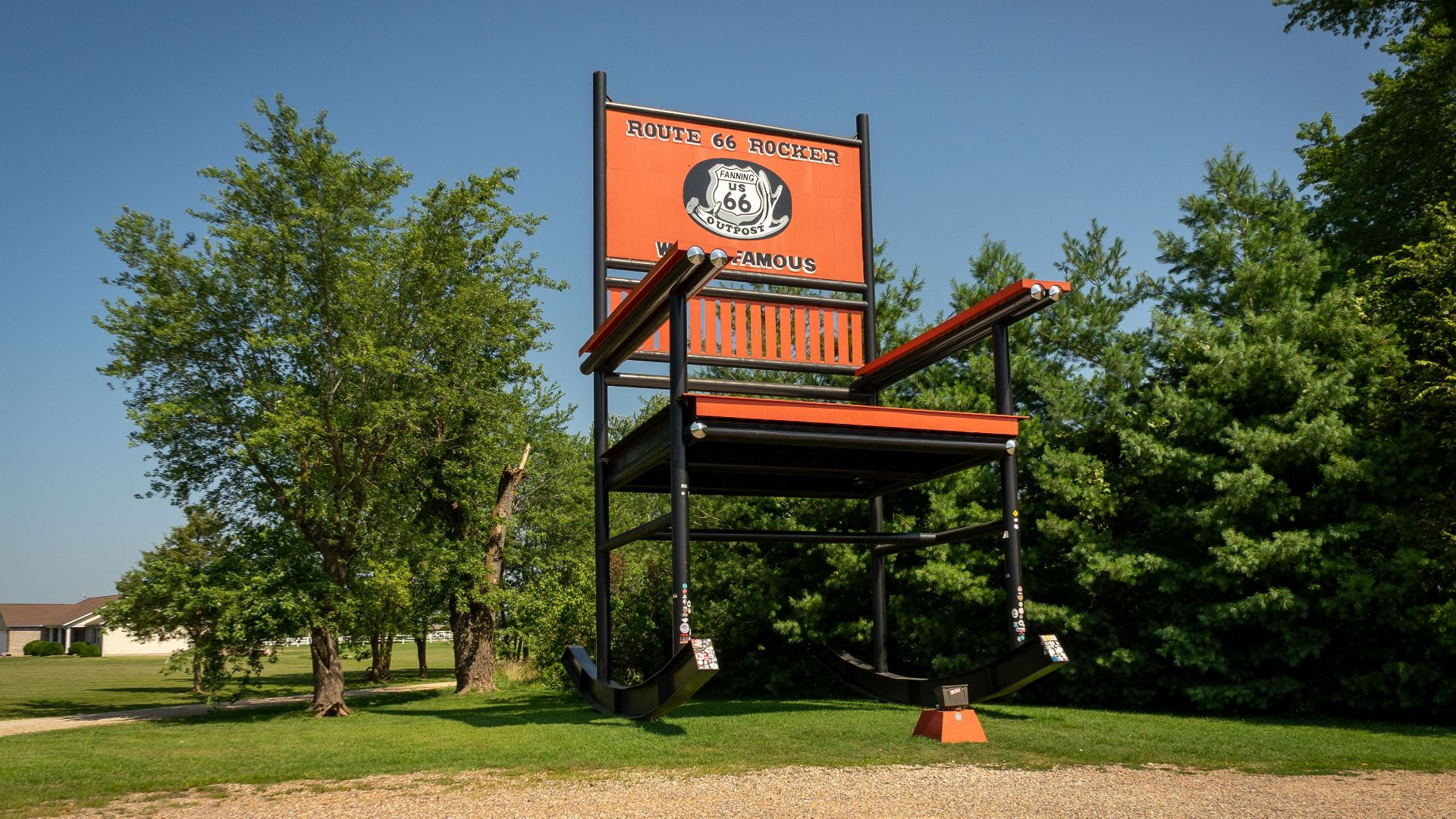 World's largest rocking chair on Route 66 among green trees under clear skies.