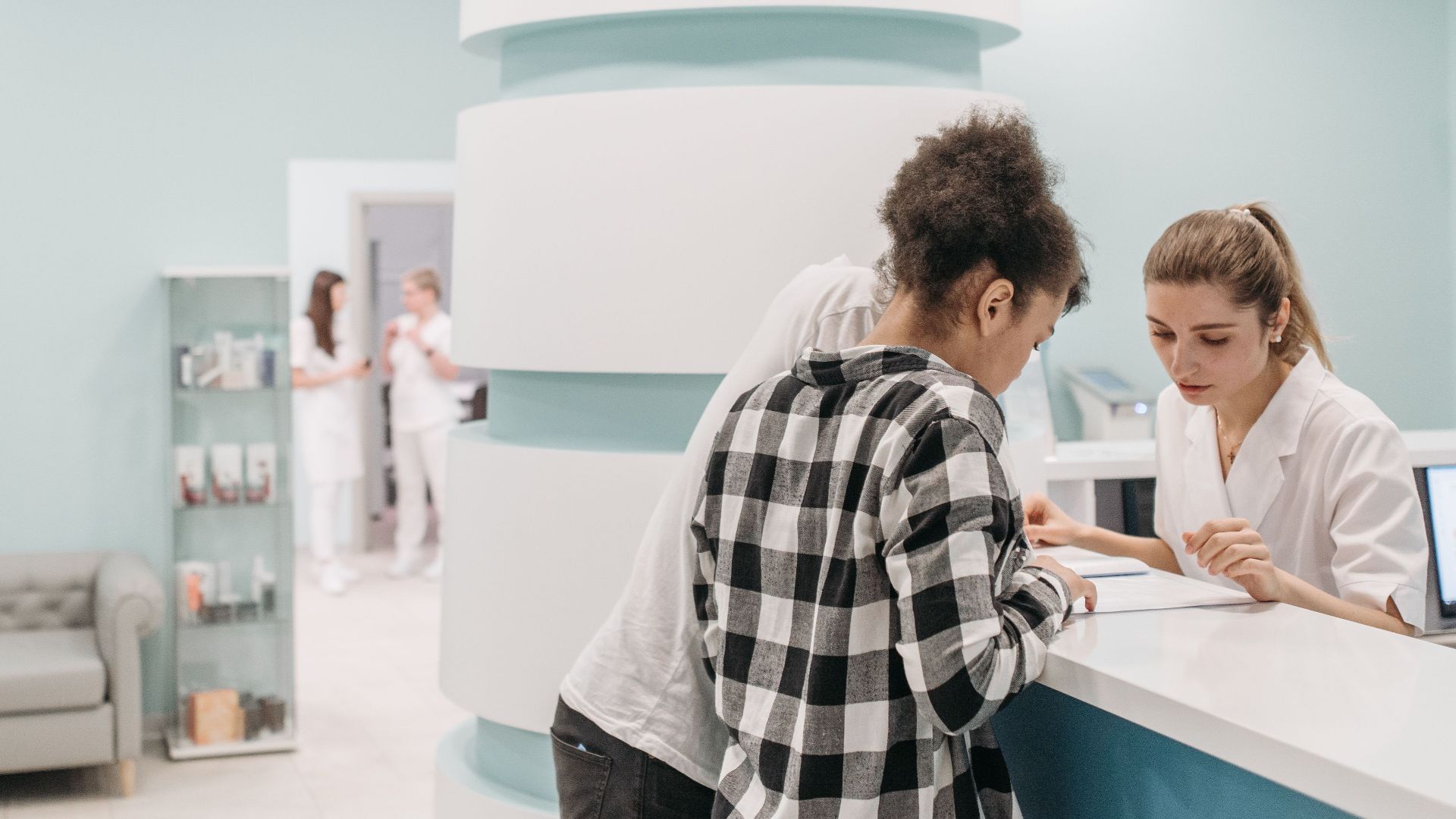 Healthcare professionals assisting at a modern clinic reception desk.