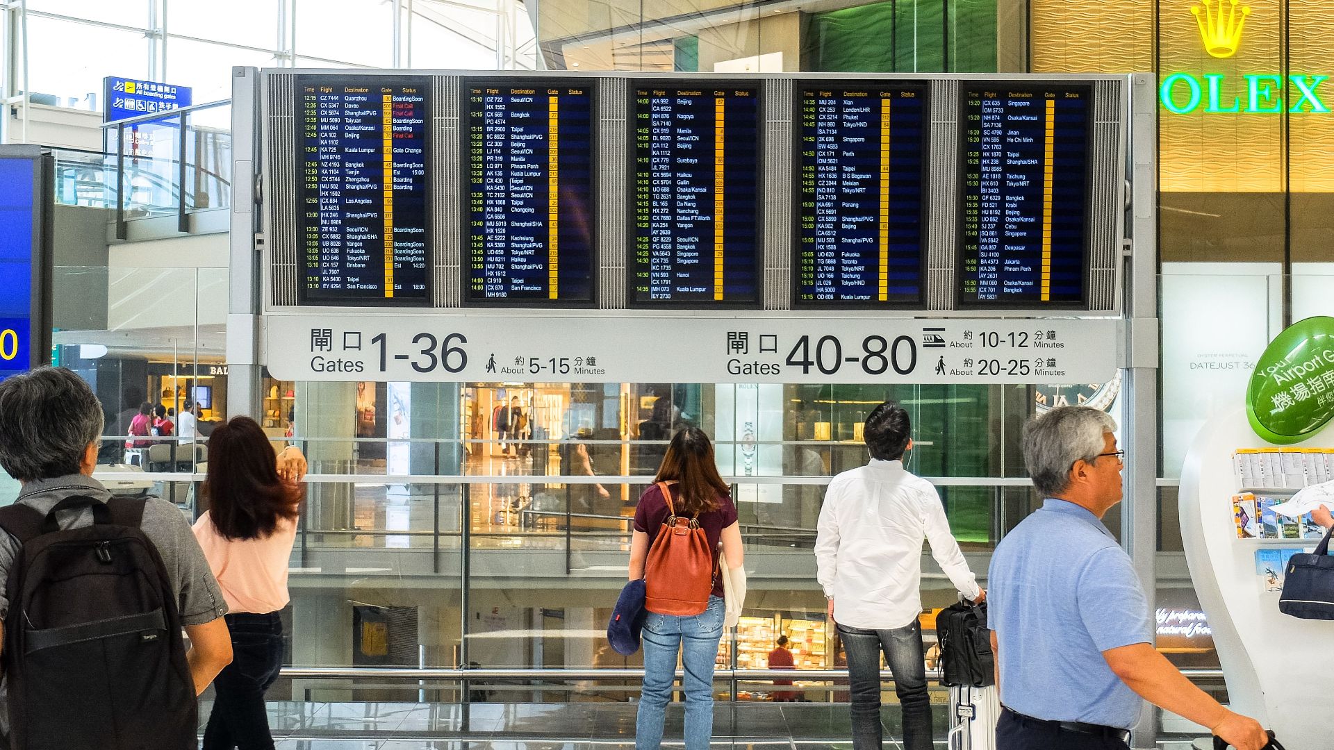 Passengers checking the departure board at Hong Kong International Airport terminal.