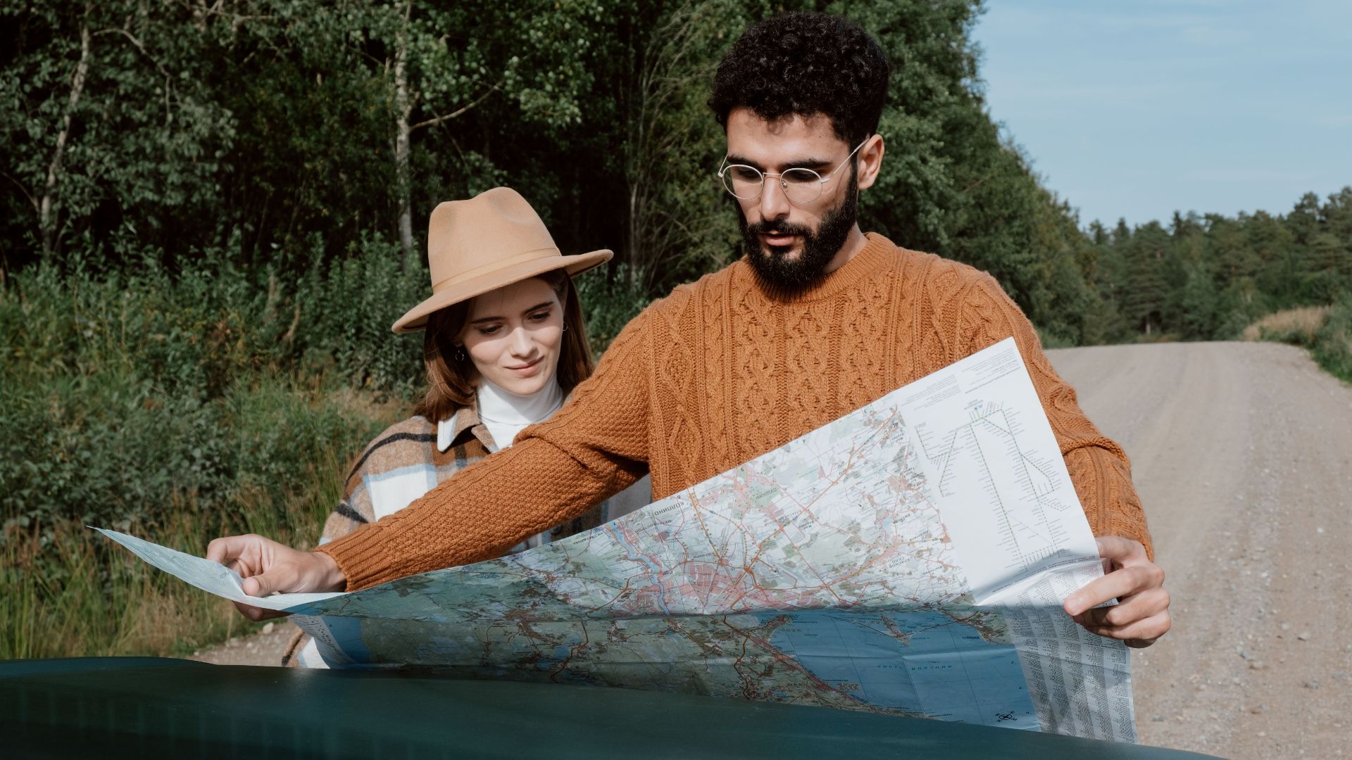A young couple examines a map on a scenic outdoor road trip.