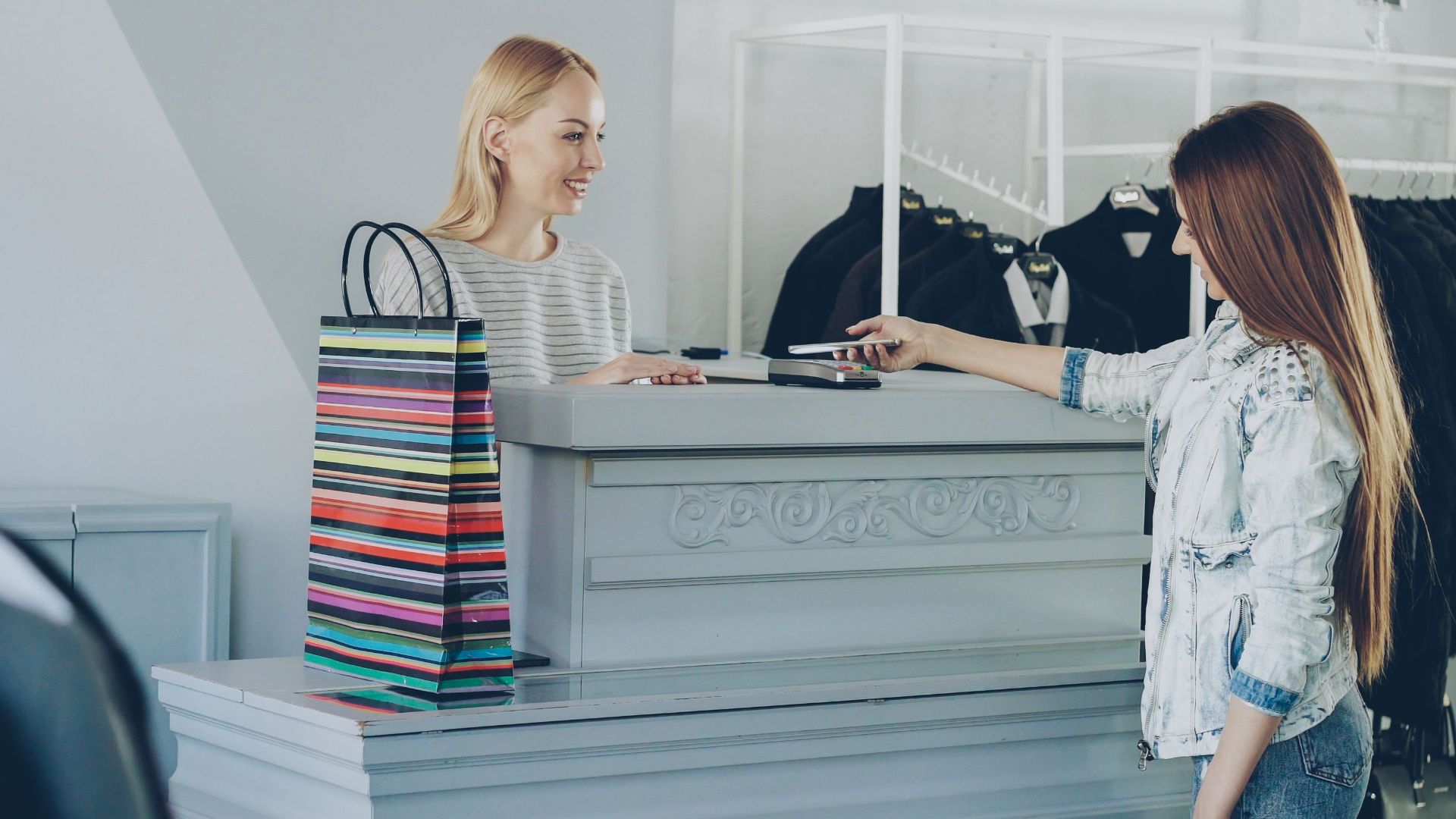 Customer interacting with cashier at boutique counter with shopping bags.