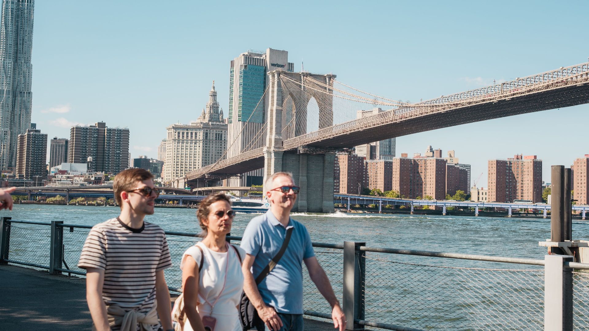 Visitors enjoy a sunny day walking near the iconic Brooklyn Bridge in New York City.
