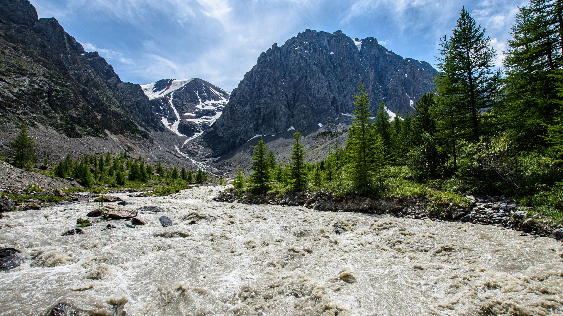 Rushing river with mountainous backdrop in Altai Republic, Russia.
