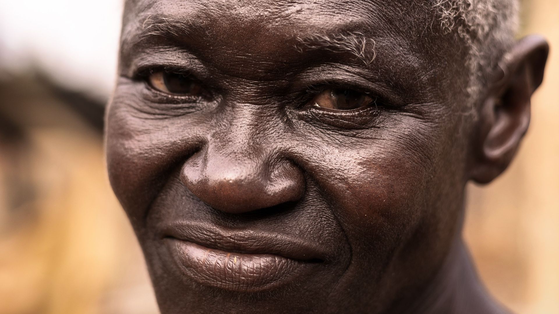 Close-up portrait of a senior adult smiling warmly outdoors, exuding positivity.
