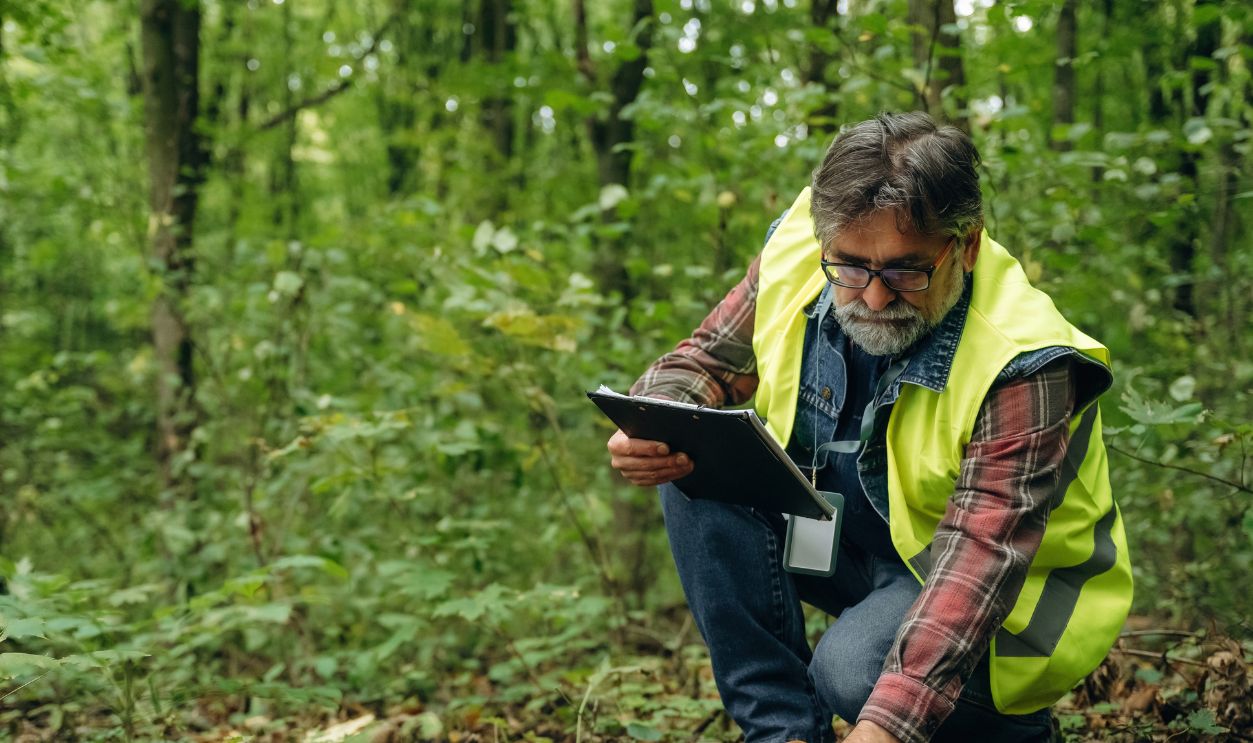 Quality control, with notepad. Senior forest ecologist is working in the woods. In the uniform.