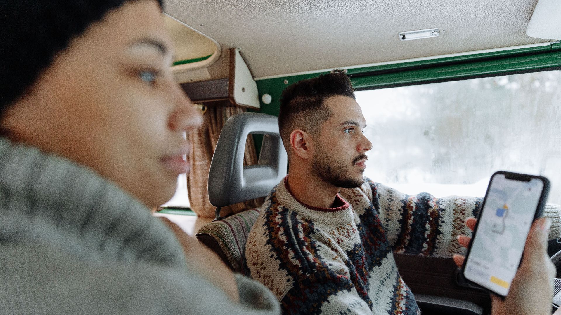 Couple using navigation app in a vintage campervan during a road trip.