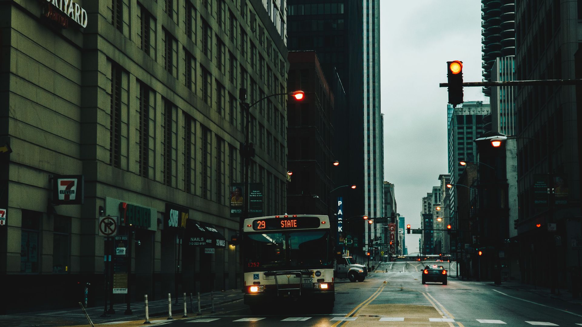 Moody urban street scene in Chicago featuring a bus and traffic lights on a rainy day.