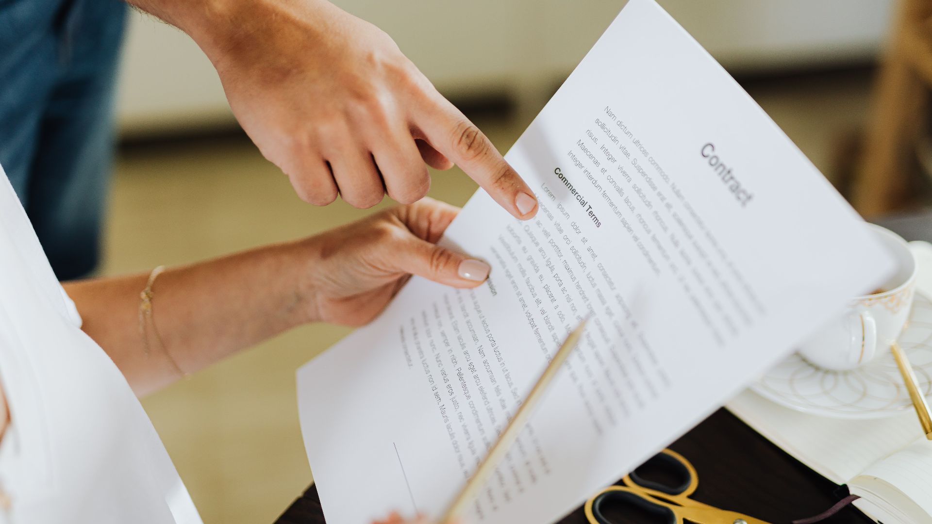 Close-up of two people discussing a business contract at a desk in an office setting.