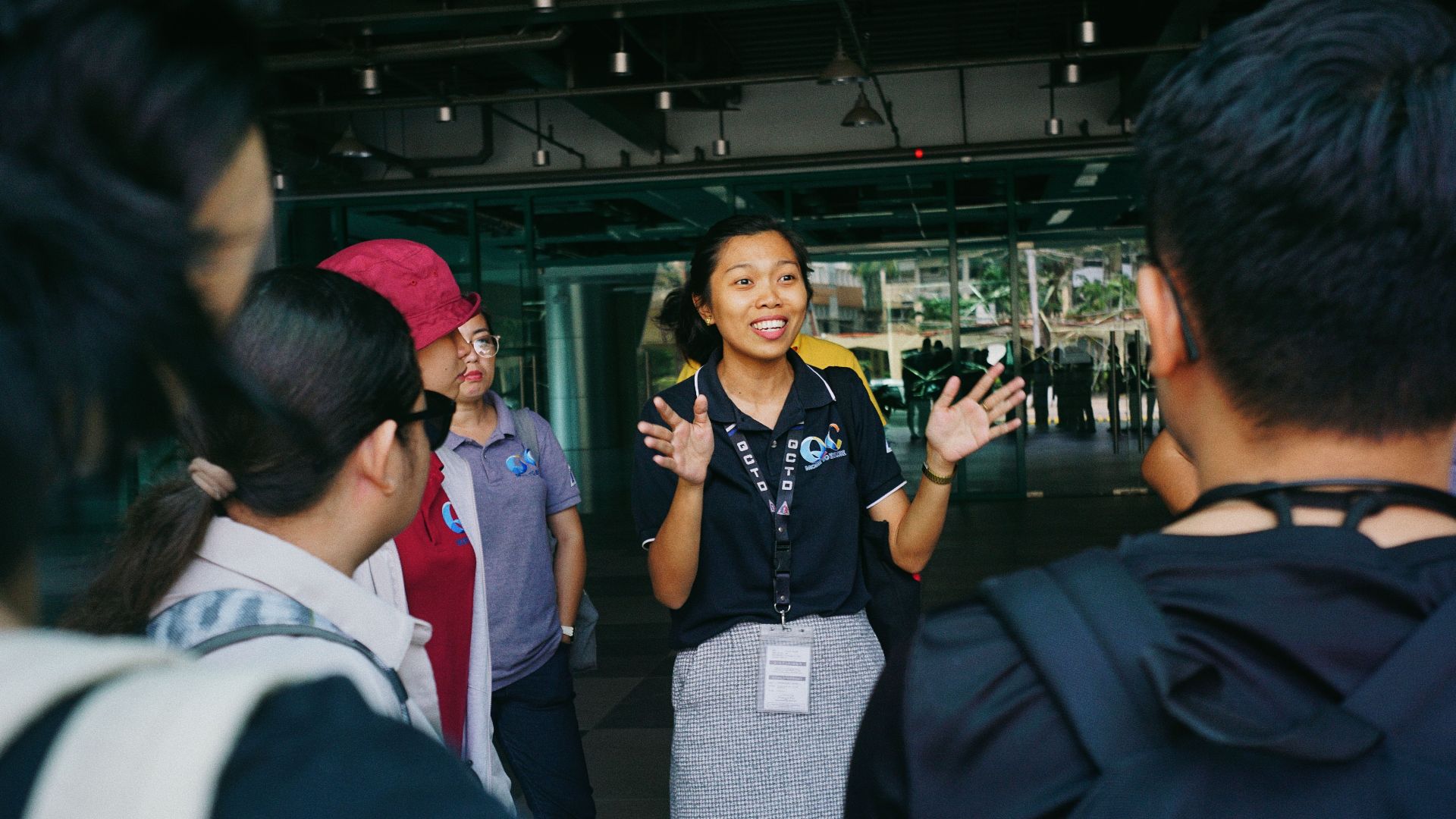 Tour guide leading a group tour, engaging visitors with gestures in an outdoor urban setting.