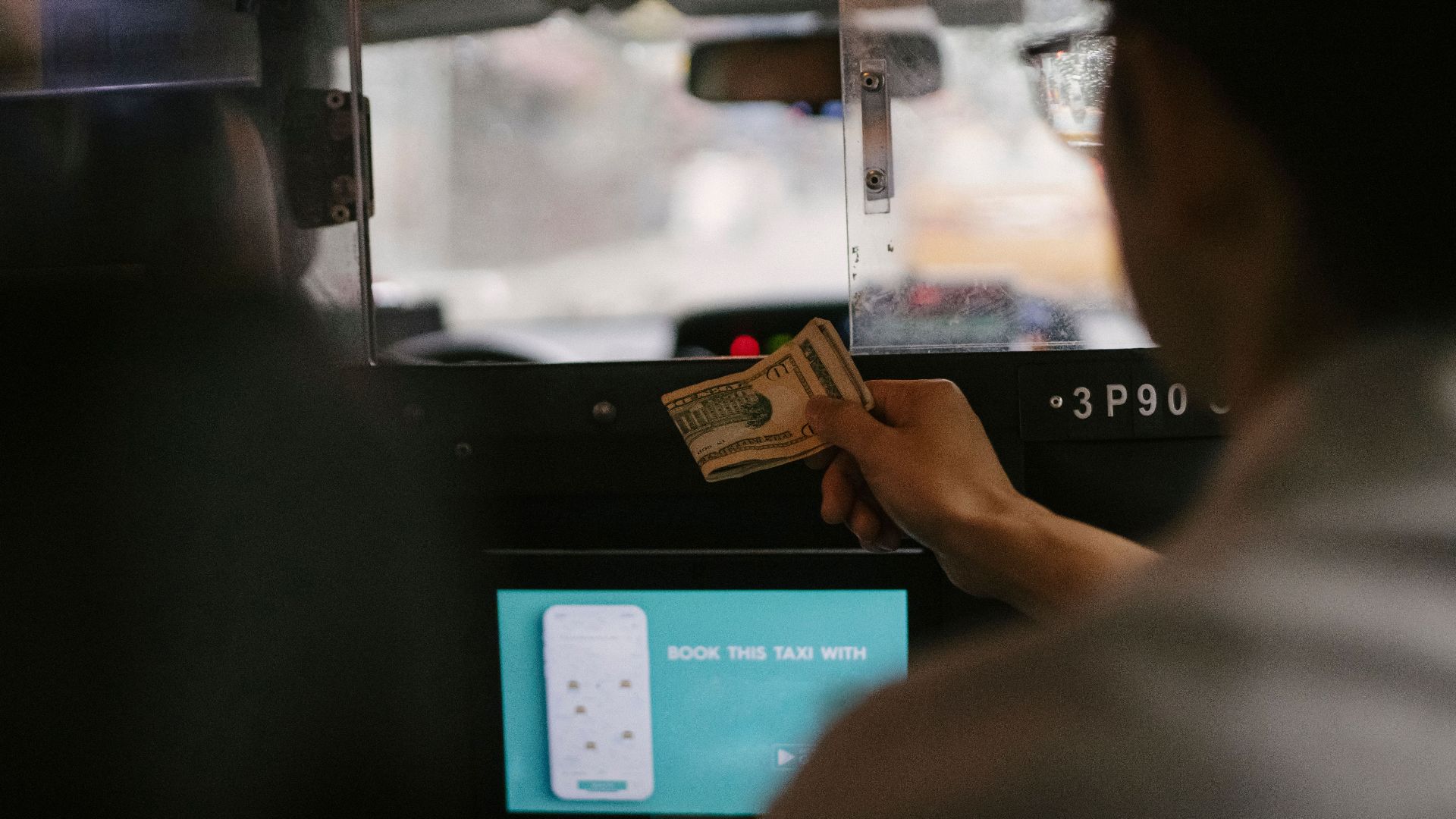 Back view of taxi car interior with tablet screen located near passenger seat and client paying for ride