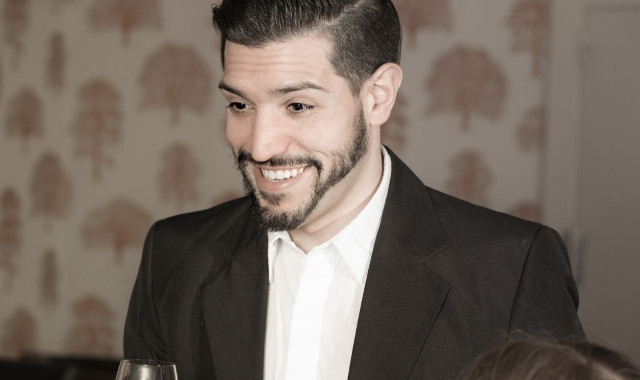 Glad bearded man pronouncing toast on friendly meeting in cozy restaurant