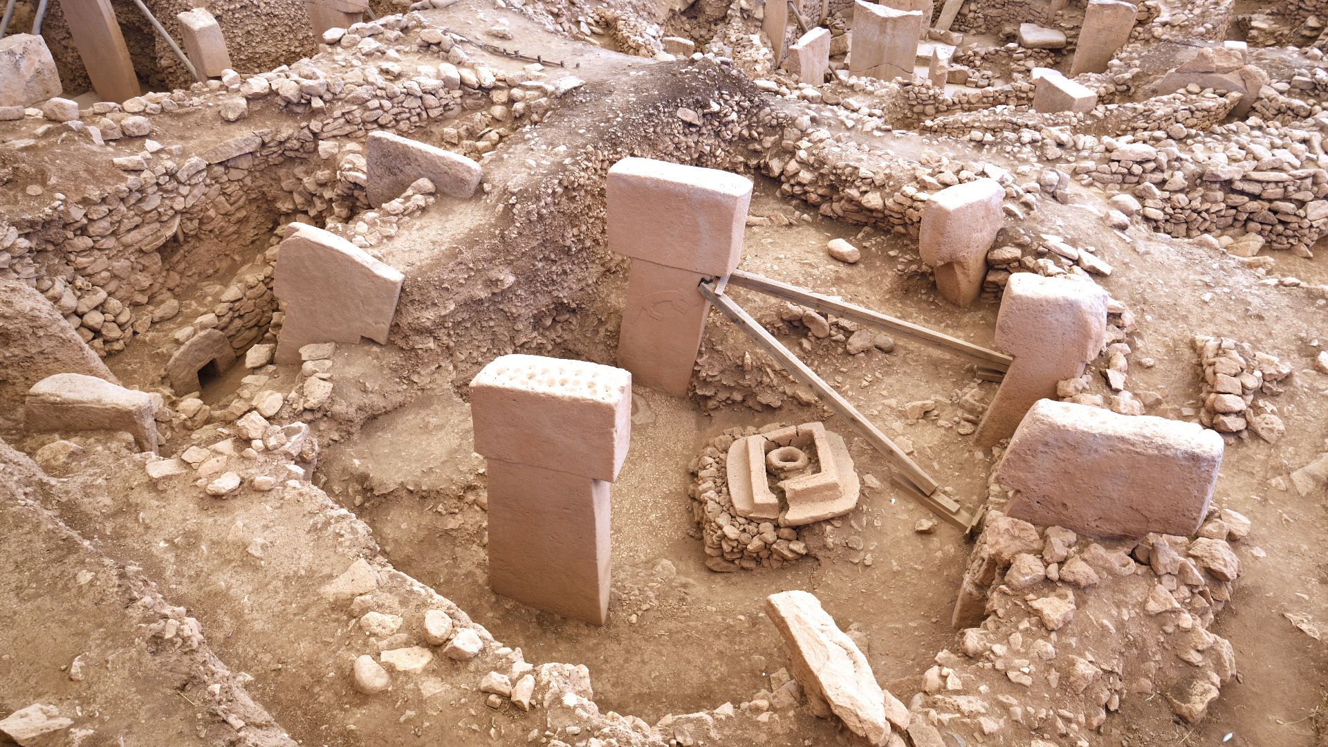 Building B is located in the Southeast-Hollow (Main Excavation Area) of Göbekli Tepe.
It has a round ground plan and measures roughly 10 metres in diameter. A total of seven T-shaped limestone pillars have so far been discovered set into its circular wal