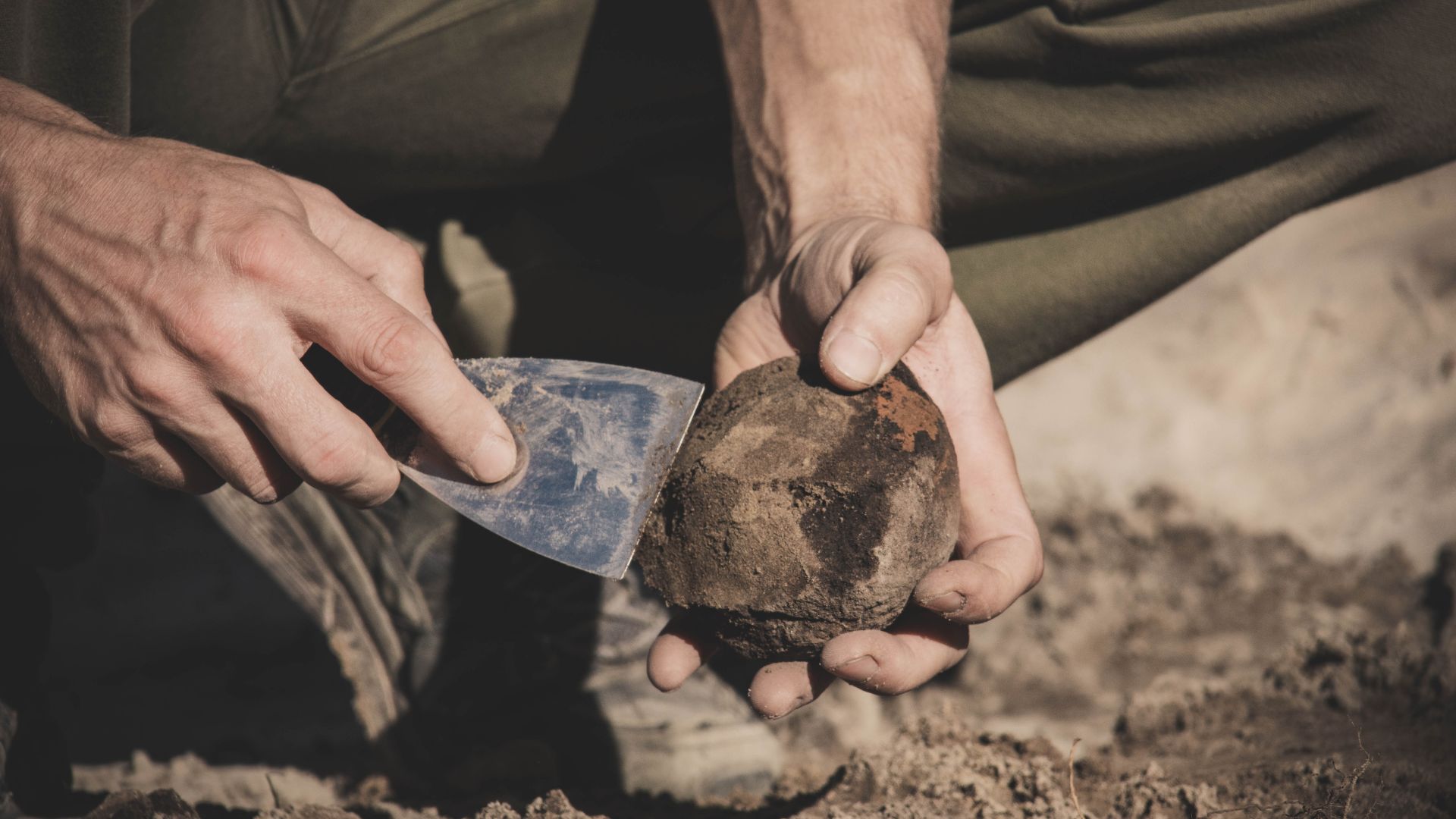 An archaeologist cleans a newly discovered artifact.  Staryi Karier multi-layer settlement (Bronze Age, Scythian period, etc), Poltava region, 2024.  Research by the archaeological expedition of the Historical and Cultural Preserve Bilsk led by Oleh Shapo