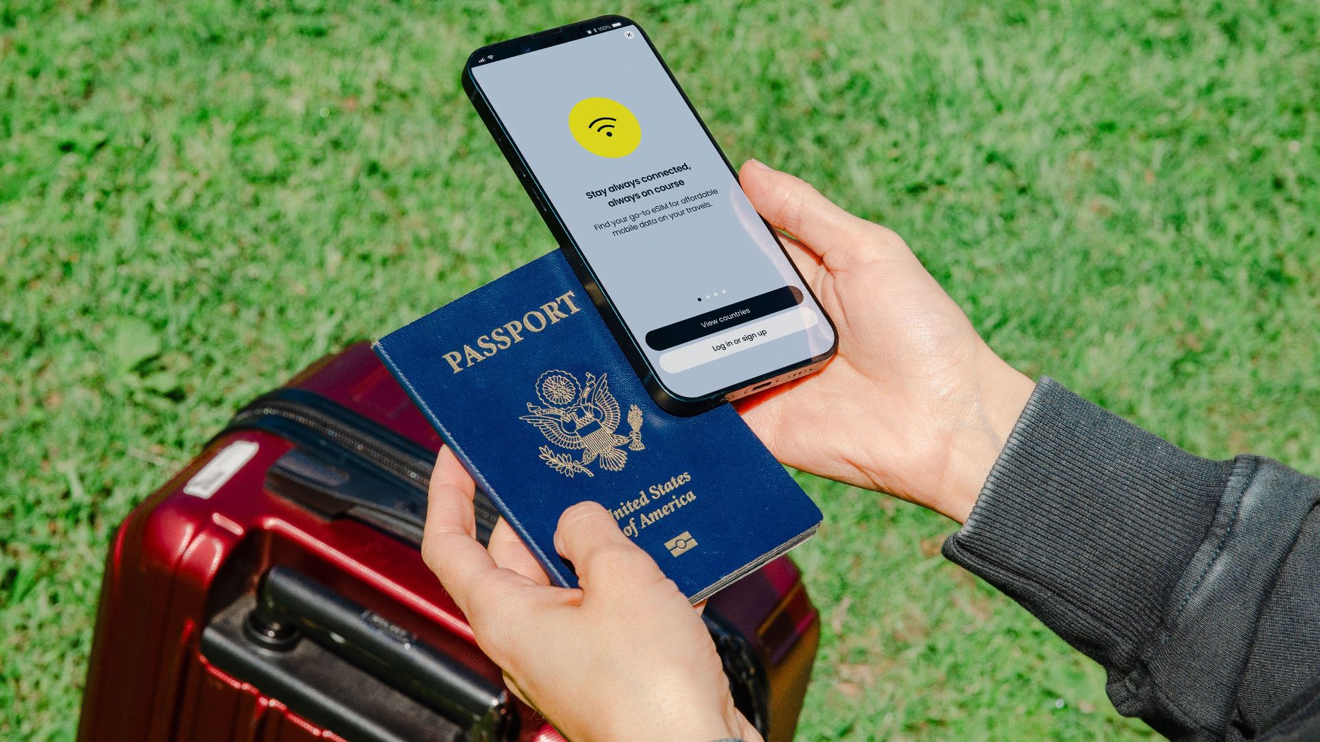Close-up of hands holding a passport and smartphone with lost connection outdoors beside luggage.