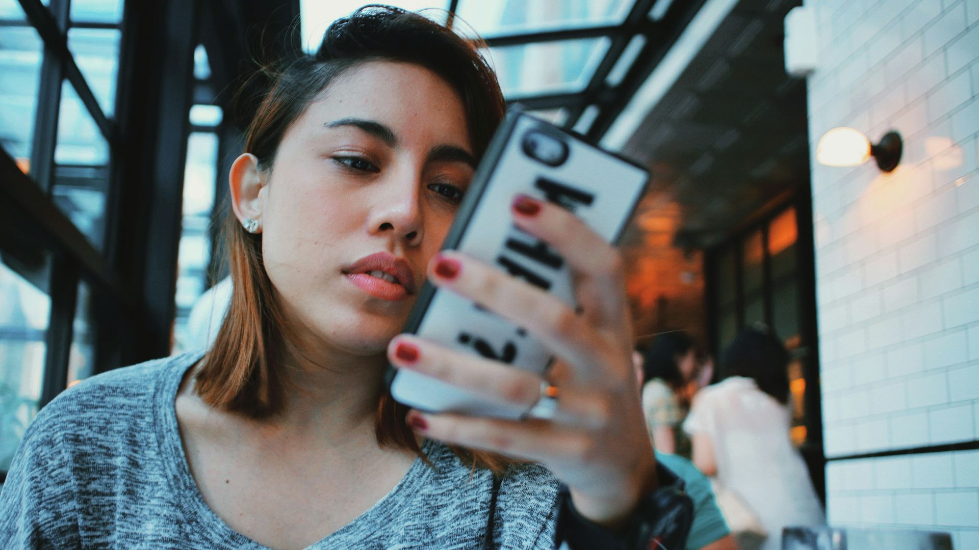 woman in gray and black sweater holding white and black iphone case