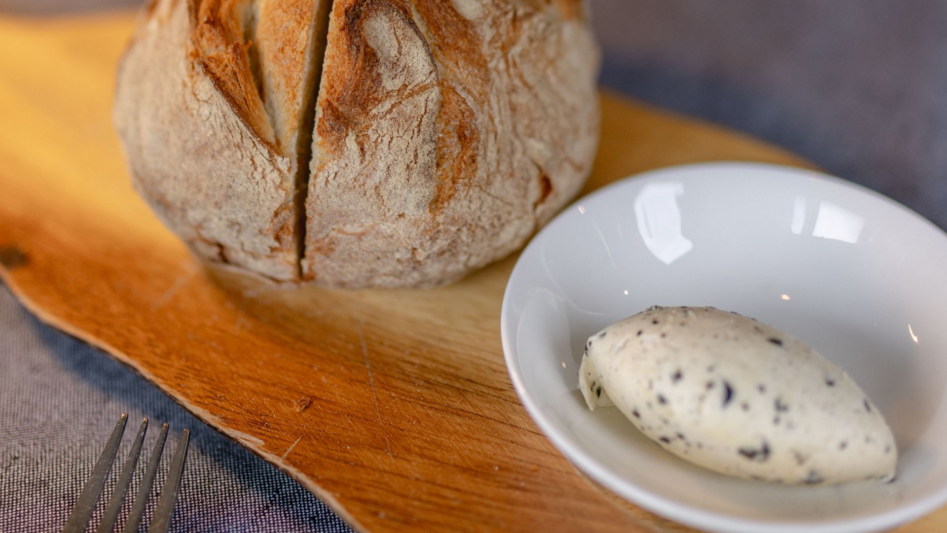 Warm artisan bread served with herb-infused butter on a rustic wooden board.