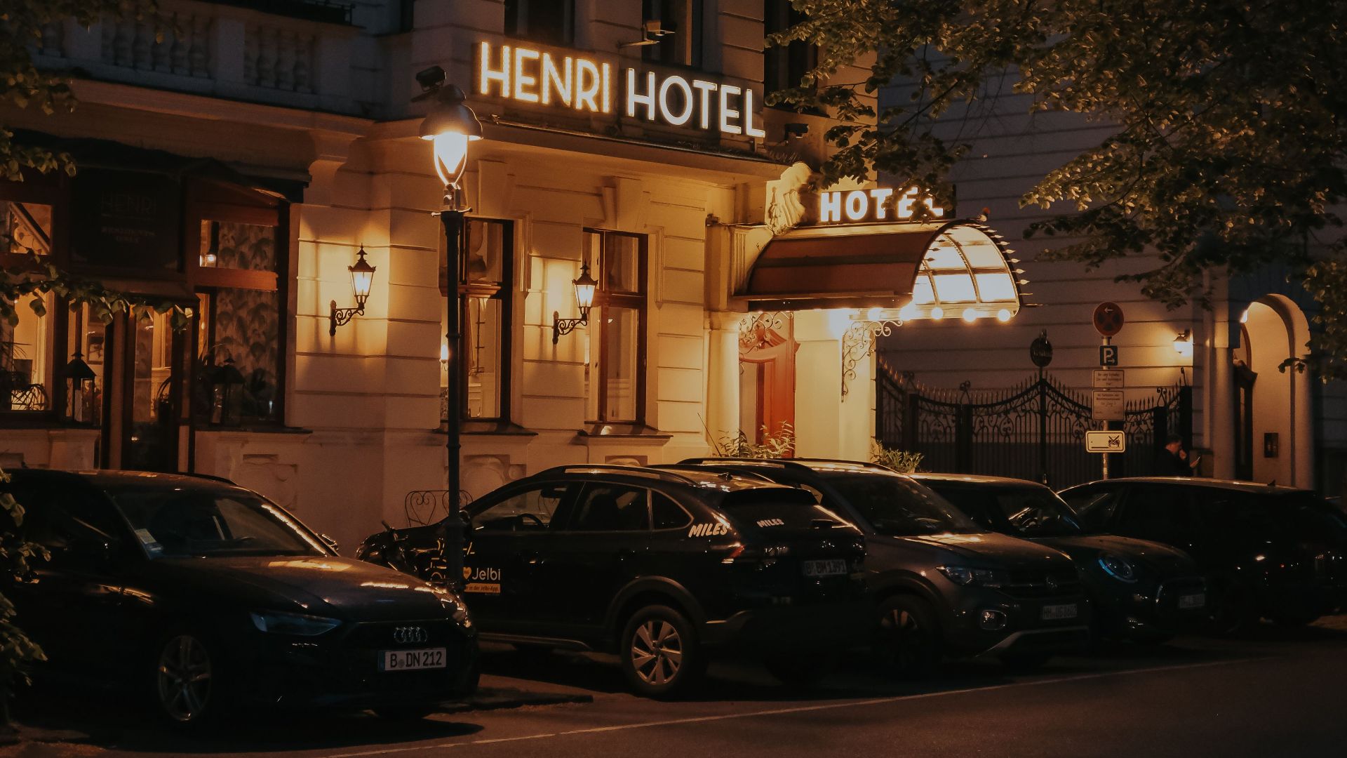 Exterior of Henri Hotel Berlin during night with parked cars and street lights.