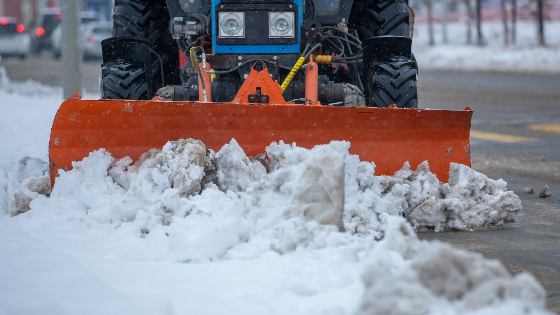 A snowplow clearing snow from a city street after a heavy winter snowstorm.