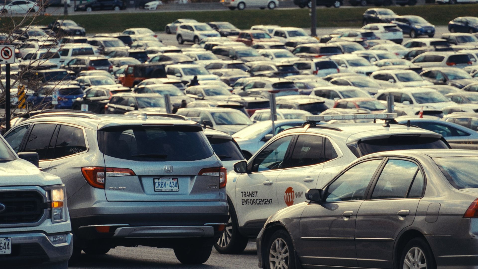 Vast and crowded car park in an urban setting during daytime, featuring various vehicles.