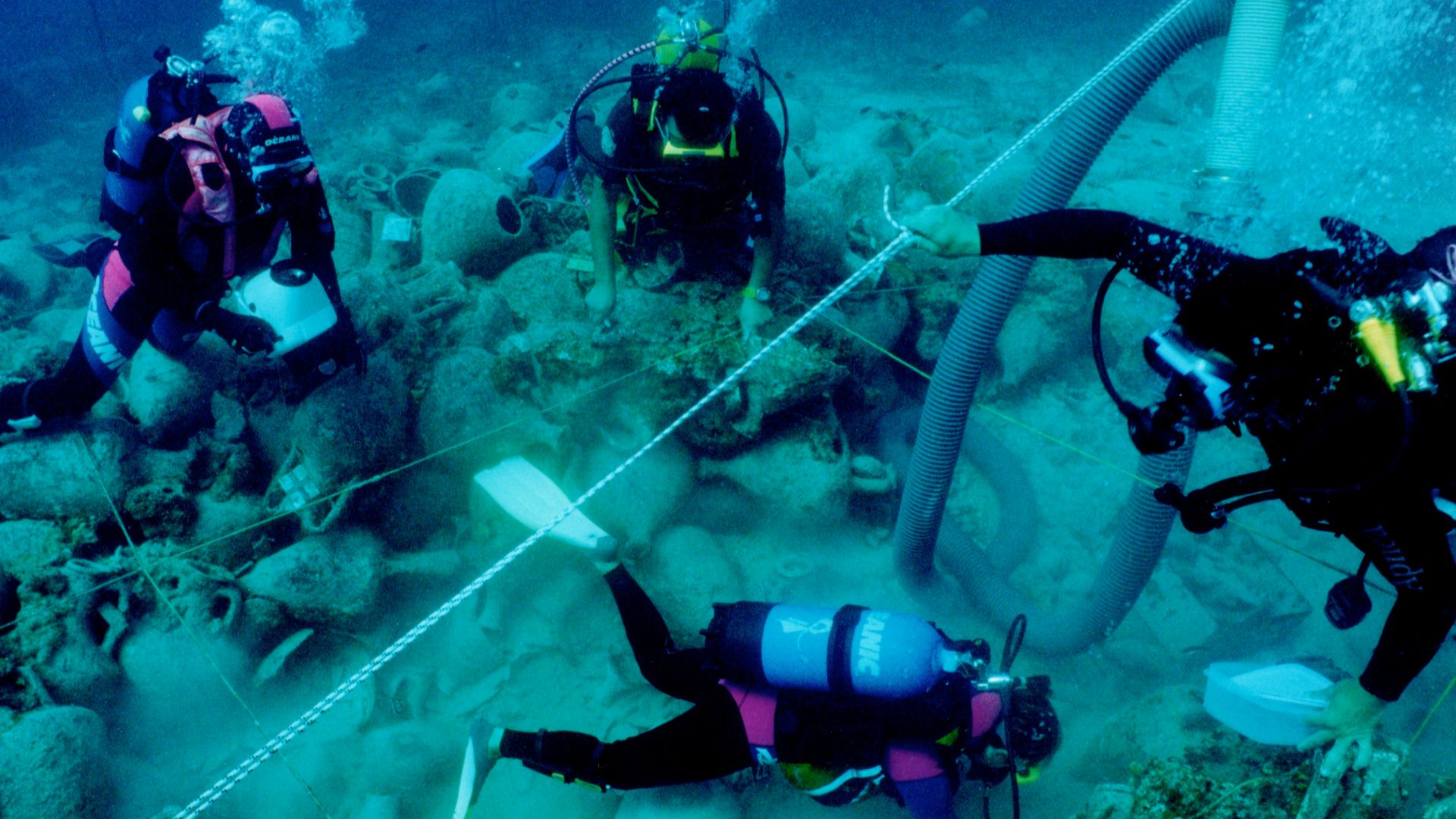 Diving archaeologists excavating the Alonnisos shipwreck in fall 2000, trench Θ3. The 2x2 m rope grid and airlift are visible.