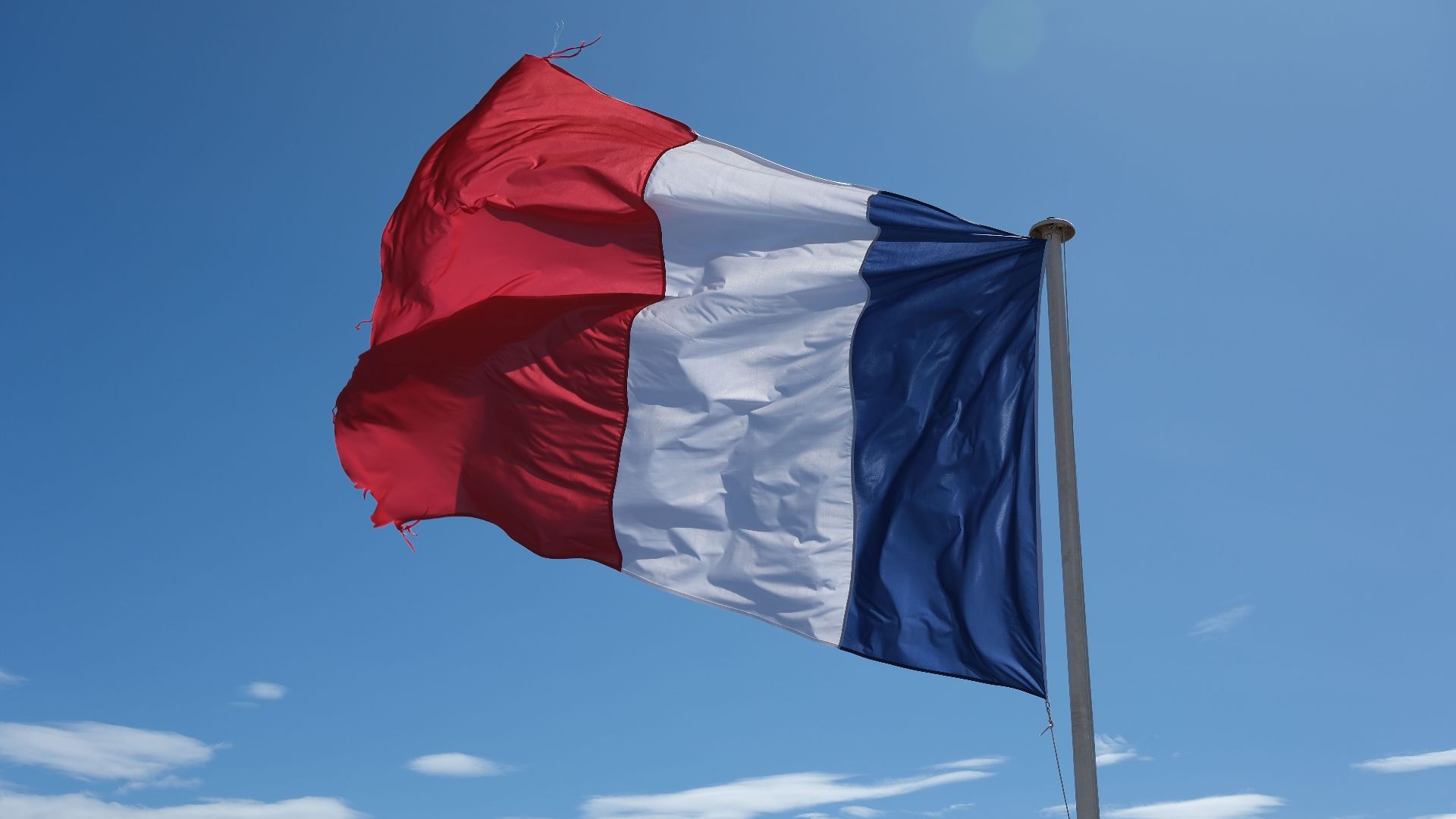 A clear blue sky with the French flag waving vibrantly, symbolizing patriotism and freedom.