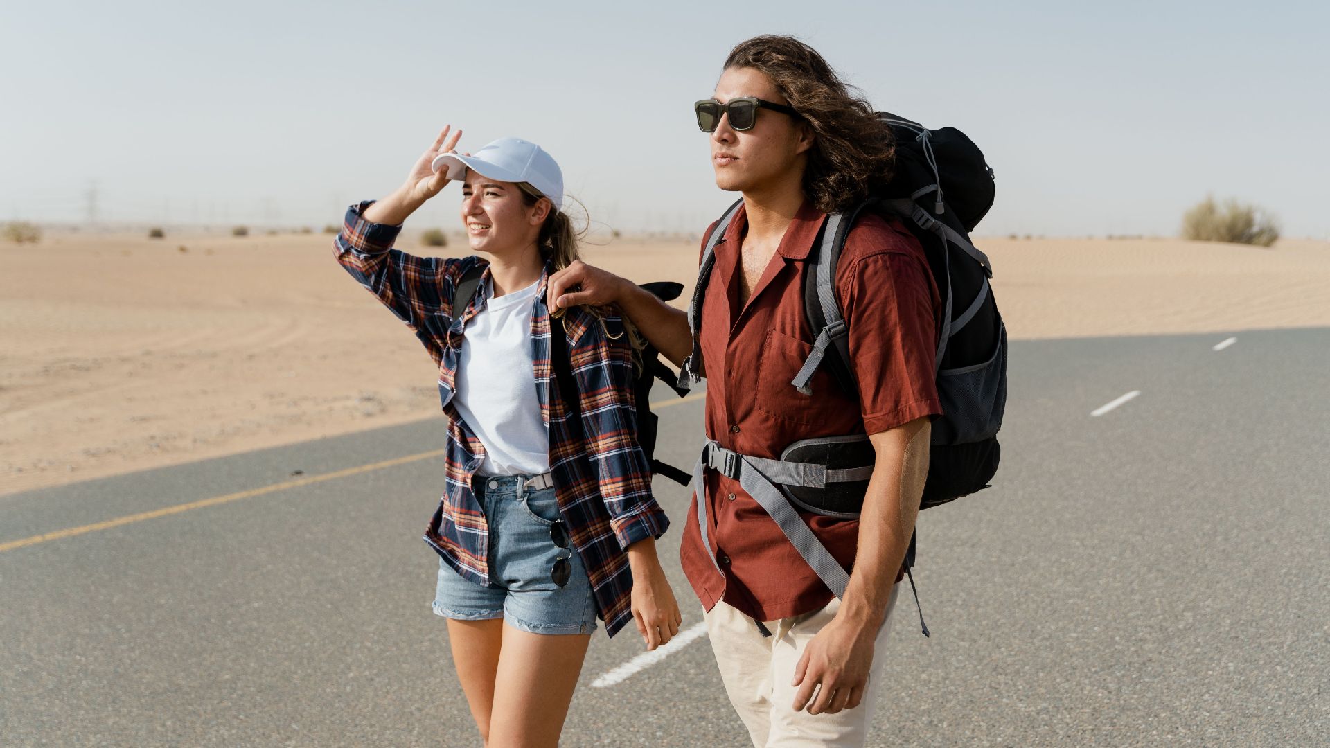 Young couple backpacking through a desert road, capturing wanderlust and exploration.