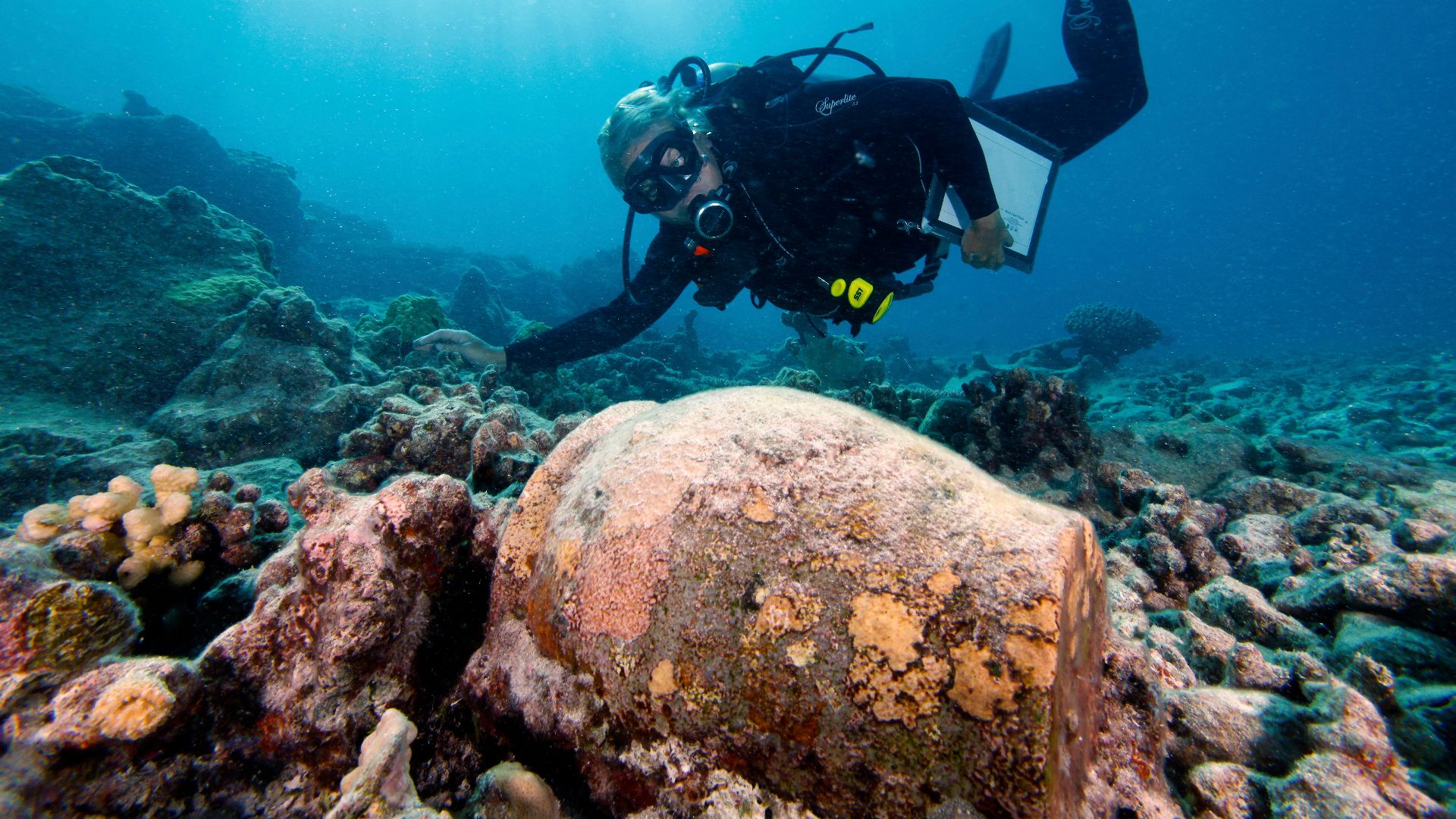 Description - Archaeologist Dr. Kelly Gleason examining a ginger jar from the whaling shipwreck site of the