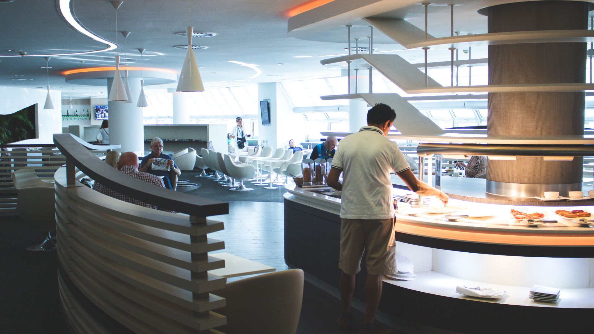 Stylish airport lounge with buffet and seating, featuring sleek interior design and contemporary furniture.