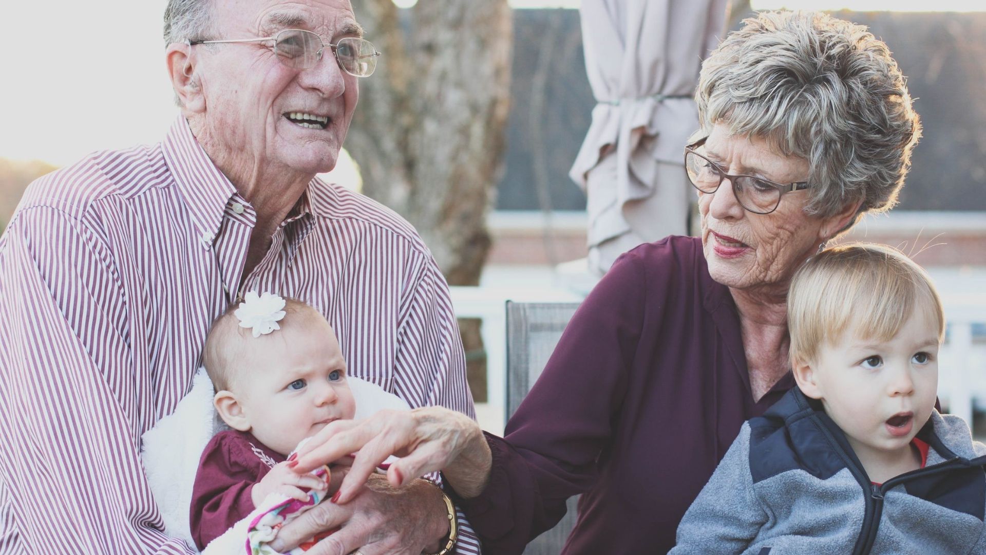 Grandparents spending joyful moments with their grandchildren in an outdoor setting, captured candidly.