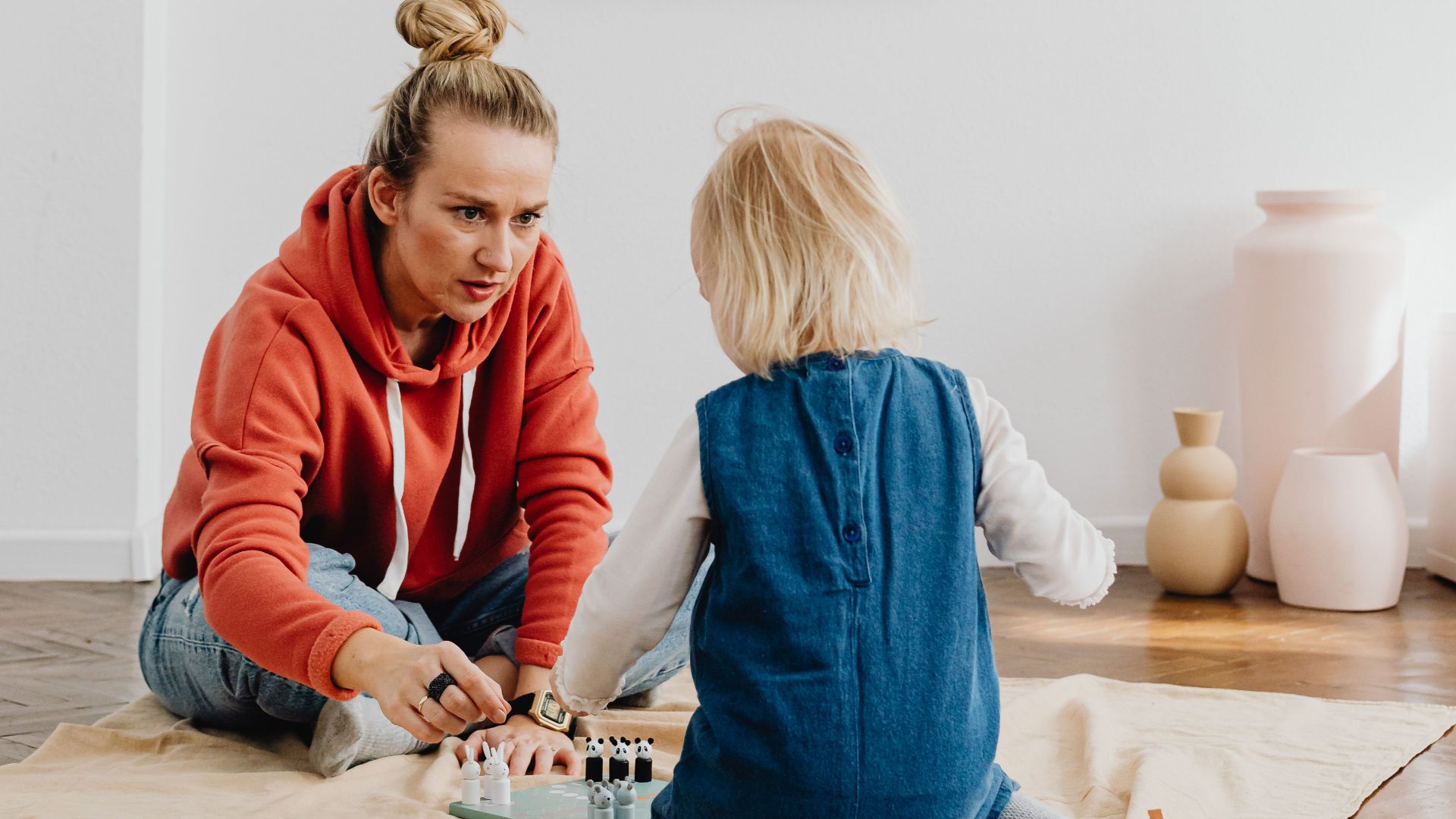 A mother and child playing a board game together indoors, fostering fun and bonding.
