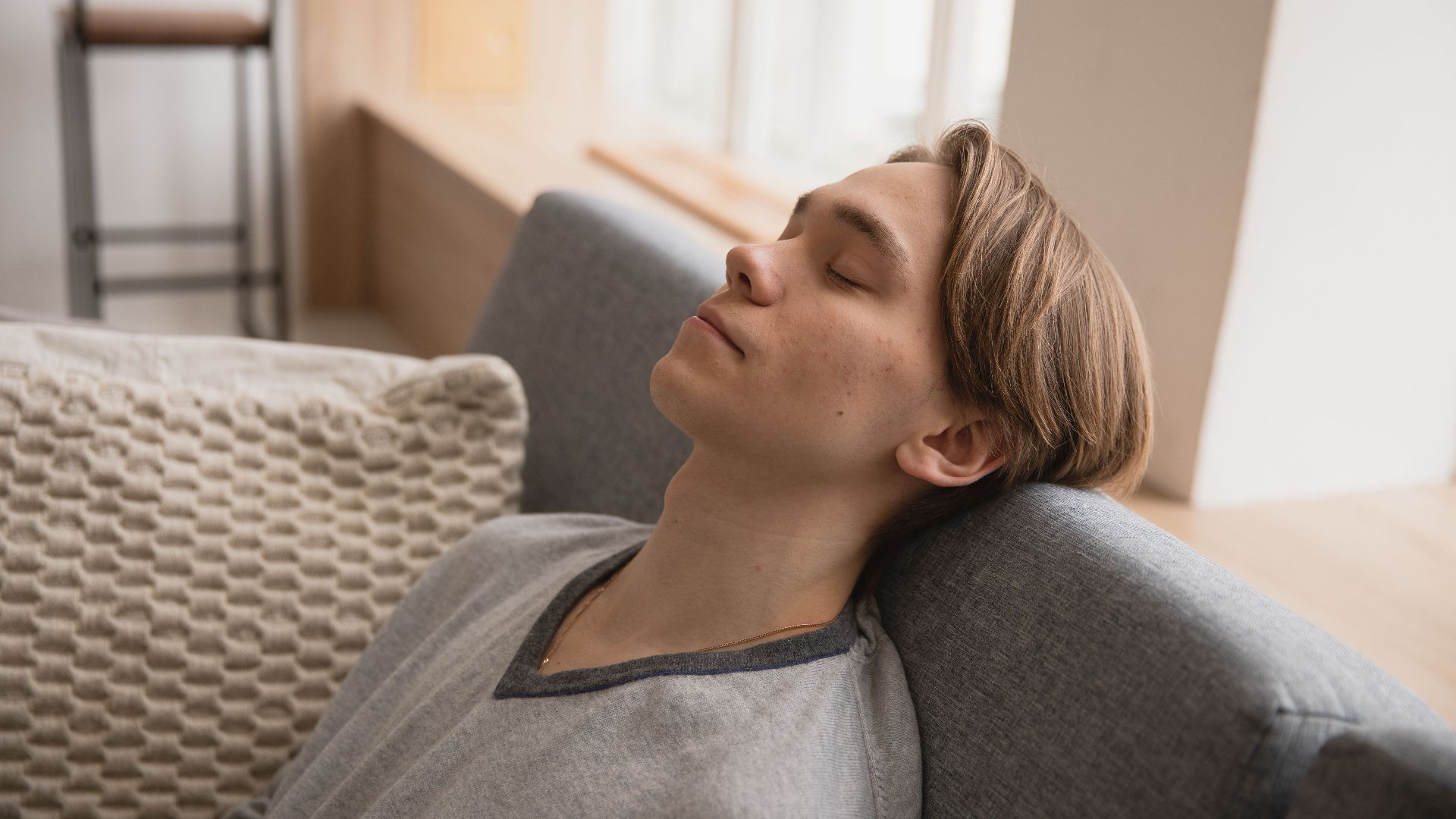 Young man relaxing on a comfortable sofa at home, enjoying a peaceful moment indoors.