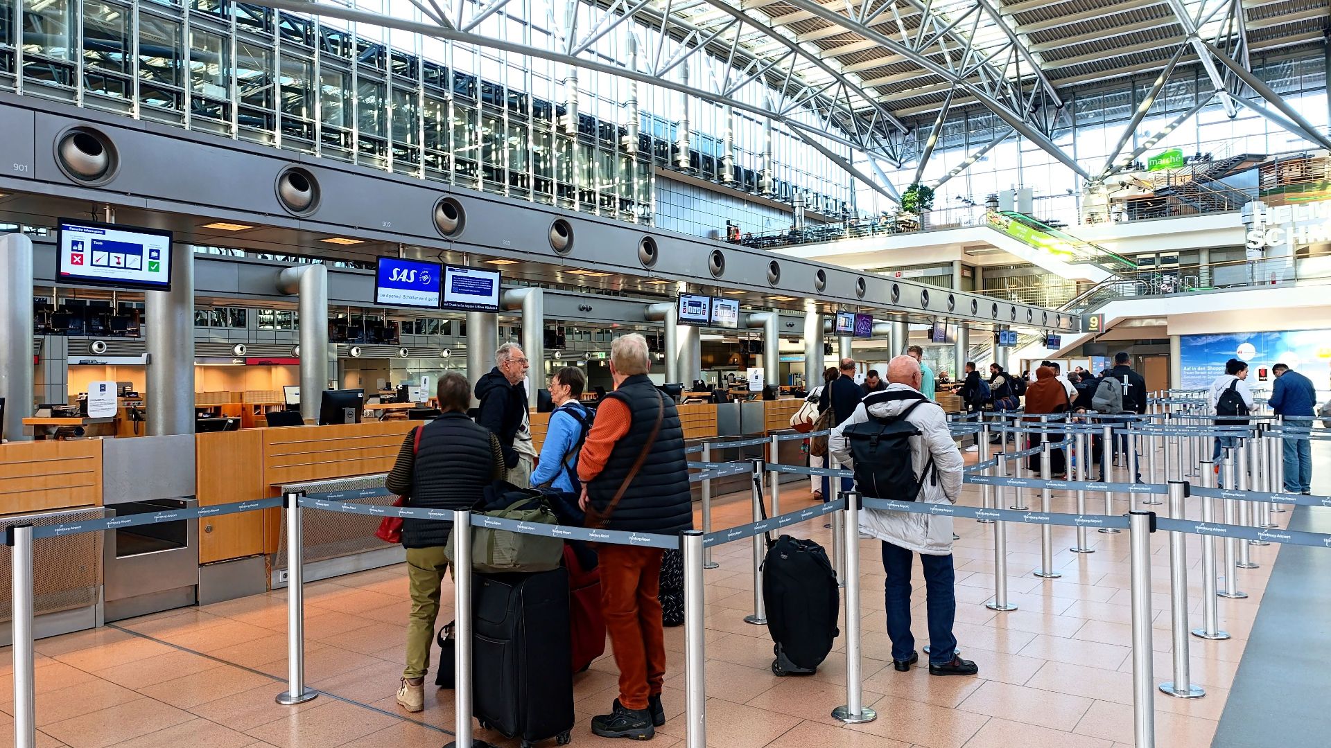 Travelers in line at Hamburg Airport's check-in counters, showcasing modern architecture.