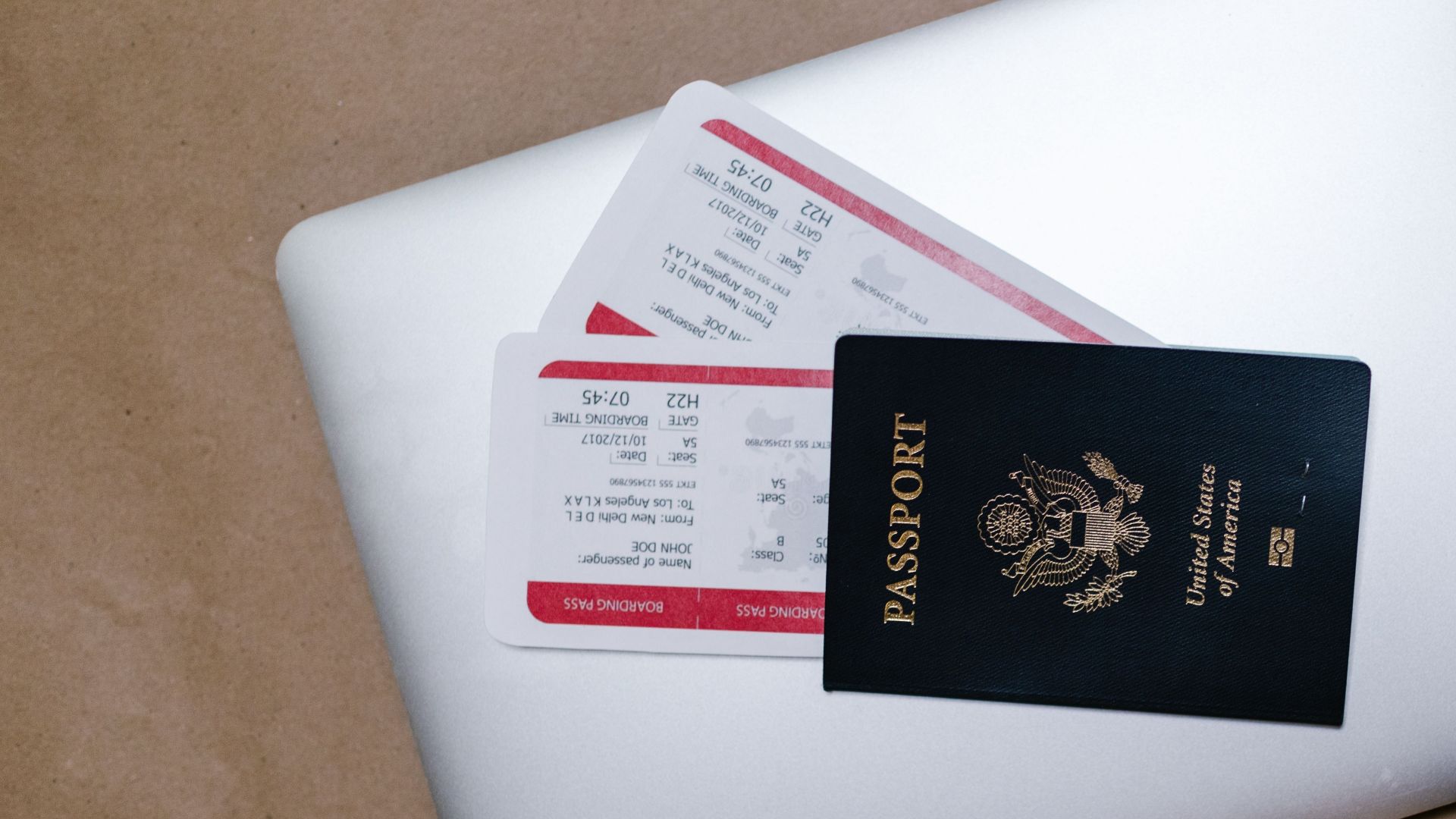 Close-up of a passport and boarding passes on a laptop, symbolizing travel preparation.