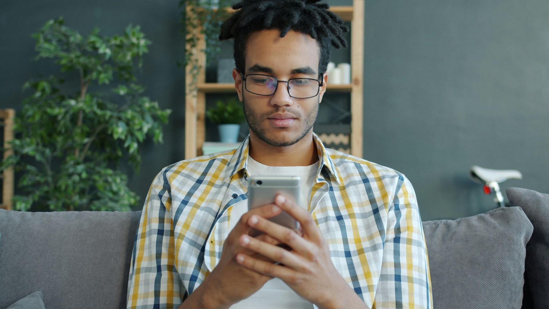 Man with glasses using a smartphone on couch