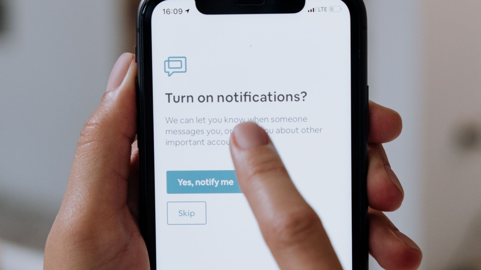Close-up of hands using a smartphone for digital notification setup.