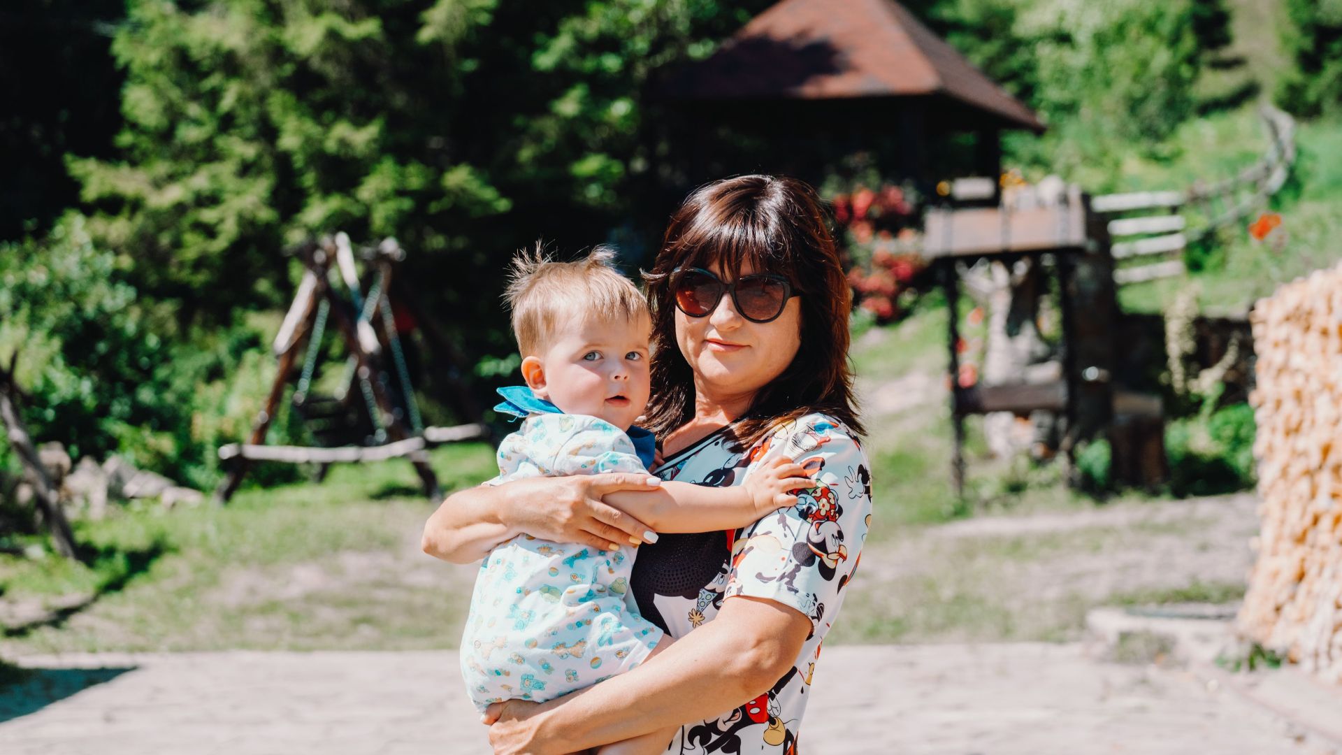 A mother holding her child in a sunny outdoor setting, enjoying family time together.