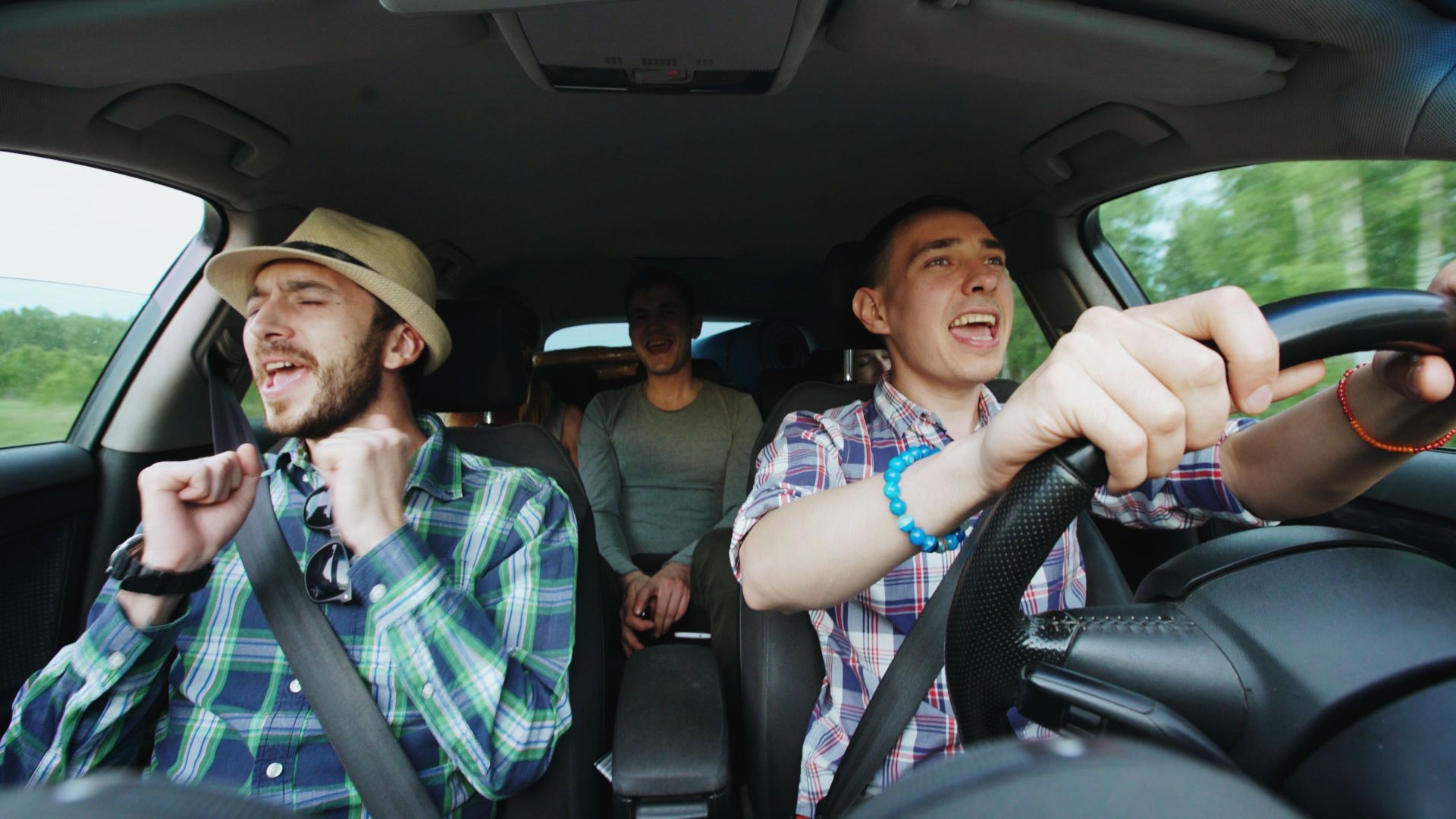 Three friends singing joyfully during a road trip, highlighting fun travel moments.