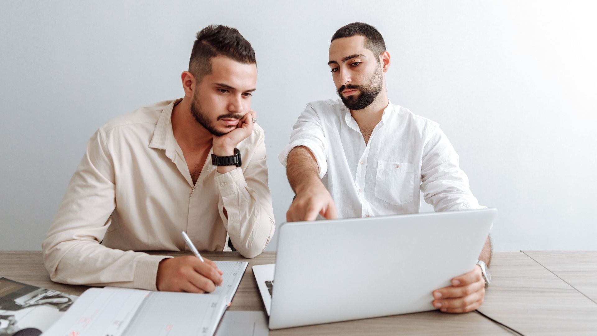 Two businessmen working together on a laptop in an office setting, focusing on a project.