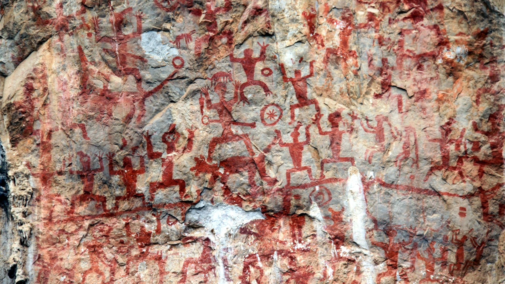 Photograph of a portions of the main rock painting of the Rock Paintings of Hua Mountain. The paintings are located on a cliff face along the west bank of the Mingjiang River in Yaoda Town, Ningming County, Guangxi, China.