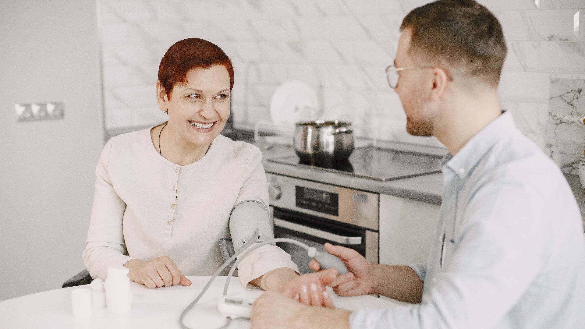 A healthcare professional checks a patient's blood pressure indoors, showcasing a friendly and caring interaction.