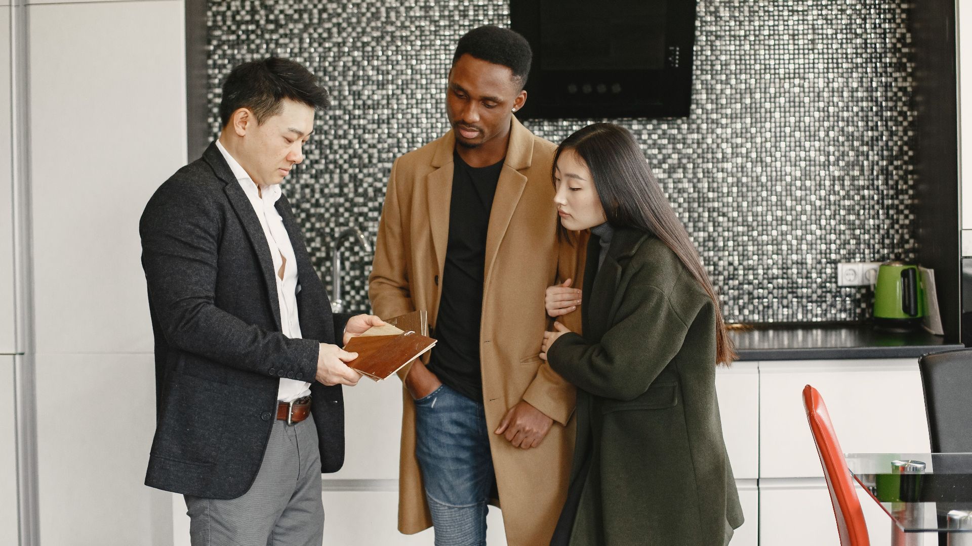 A business meeting in a contemporary kitchen showing diverse professionals discussing strategic options.
