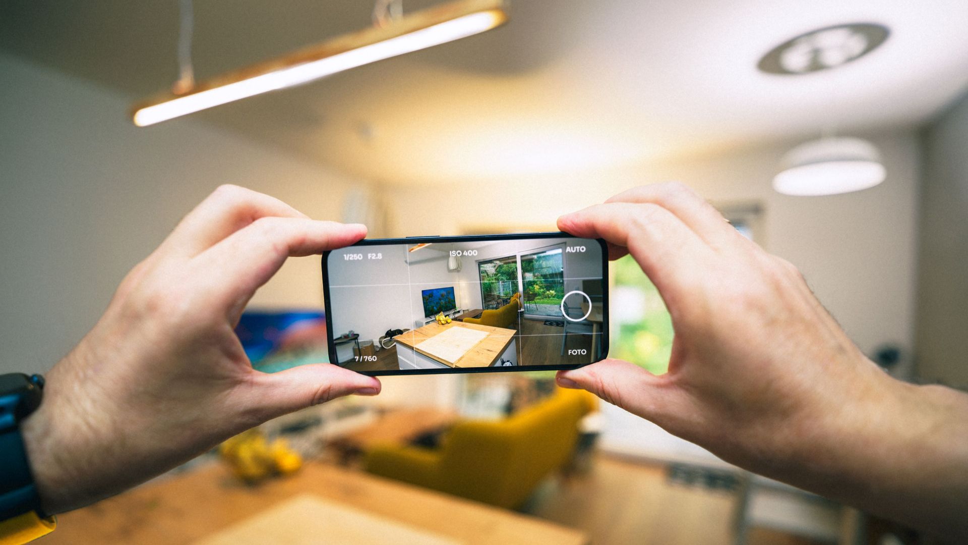 Hands capturing a modern living room interior with a smartphone.