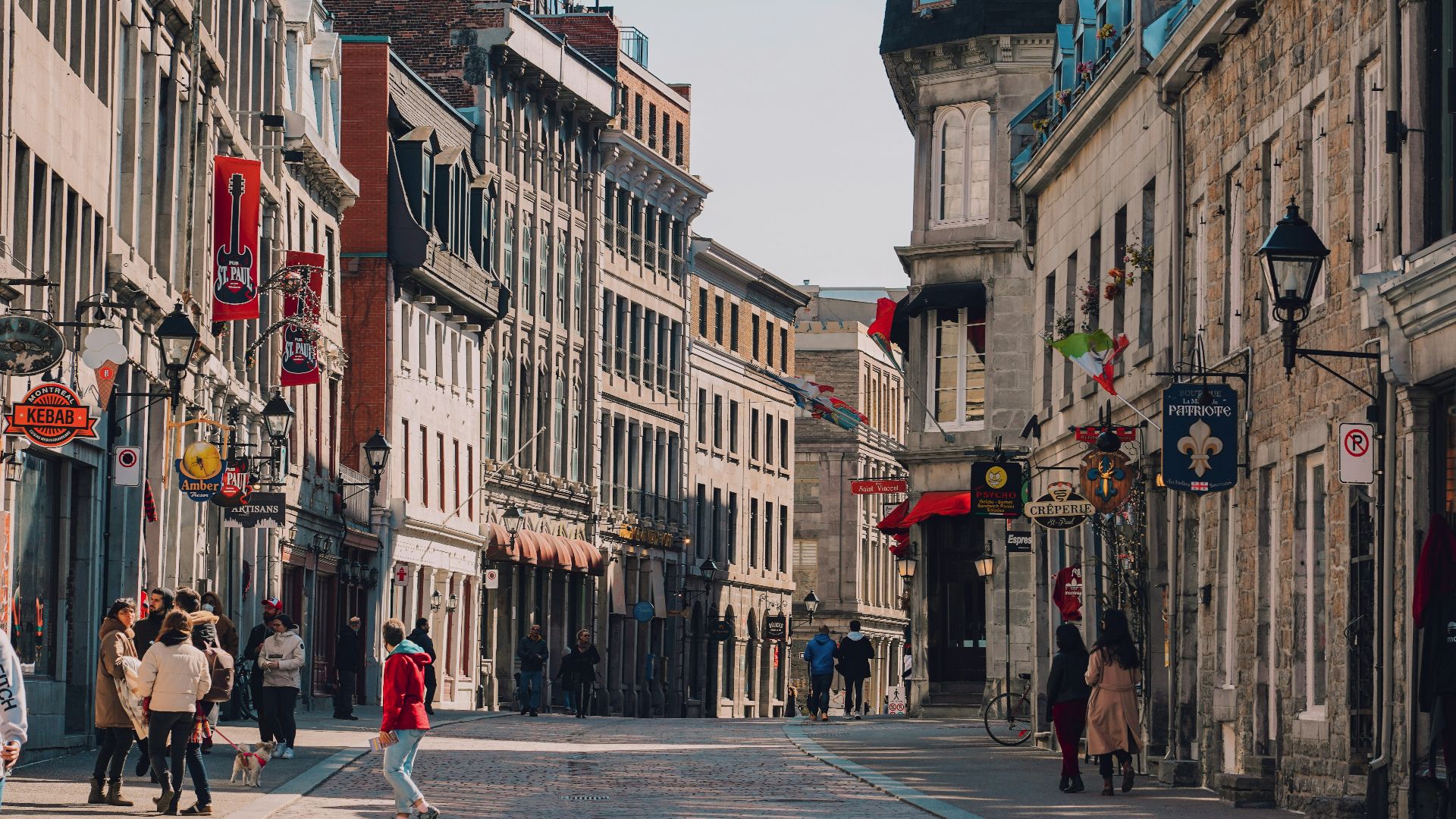 a group of people walking down a street next to tall buildings
