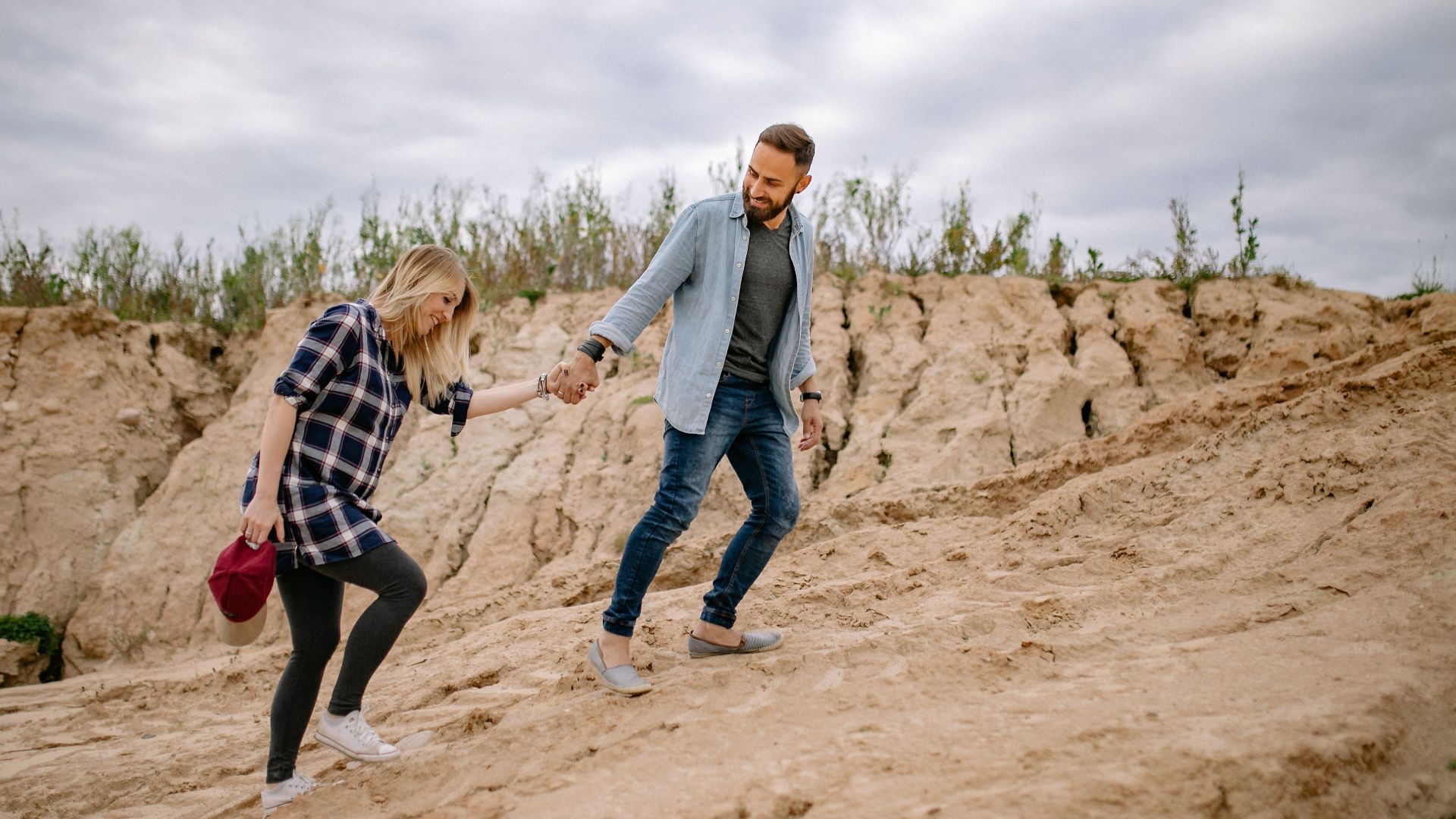Couple hiking on a rocky trail holding hands, enjoying outdoor adventure.