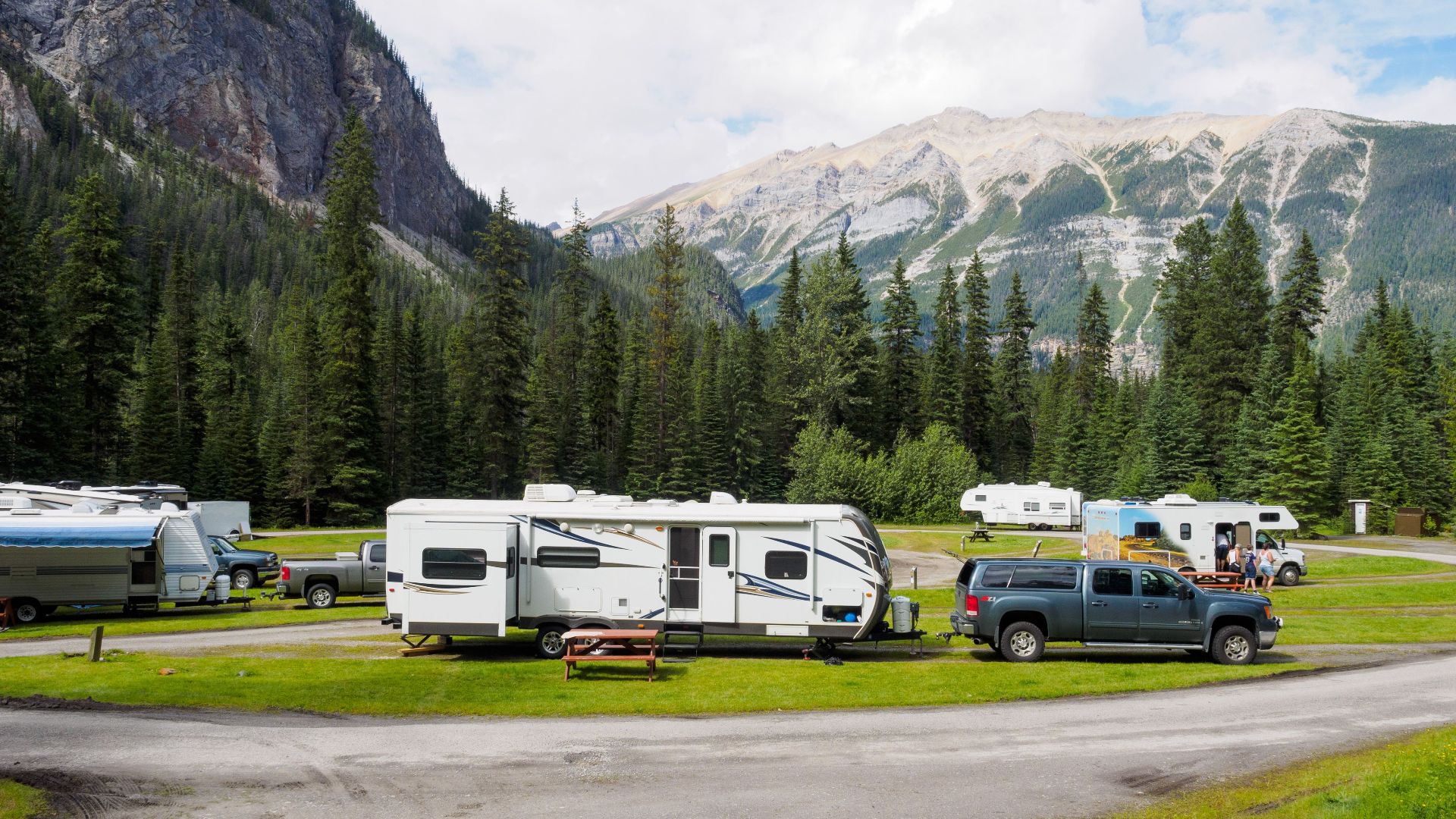 A beautiful campsite featuring RVs amidst lush forests and towering mountains for a peaceful getaway.