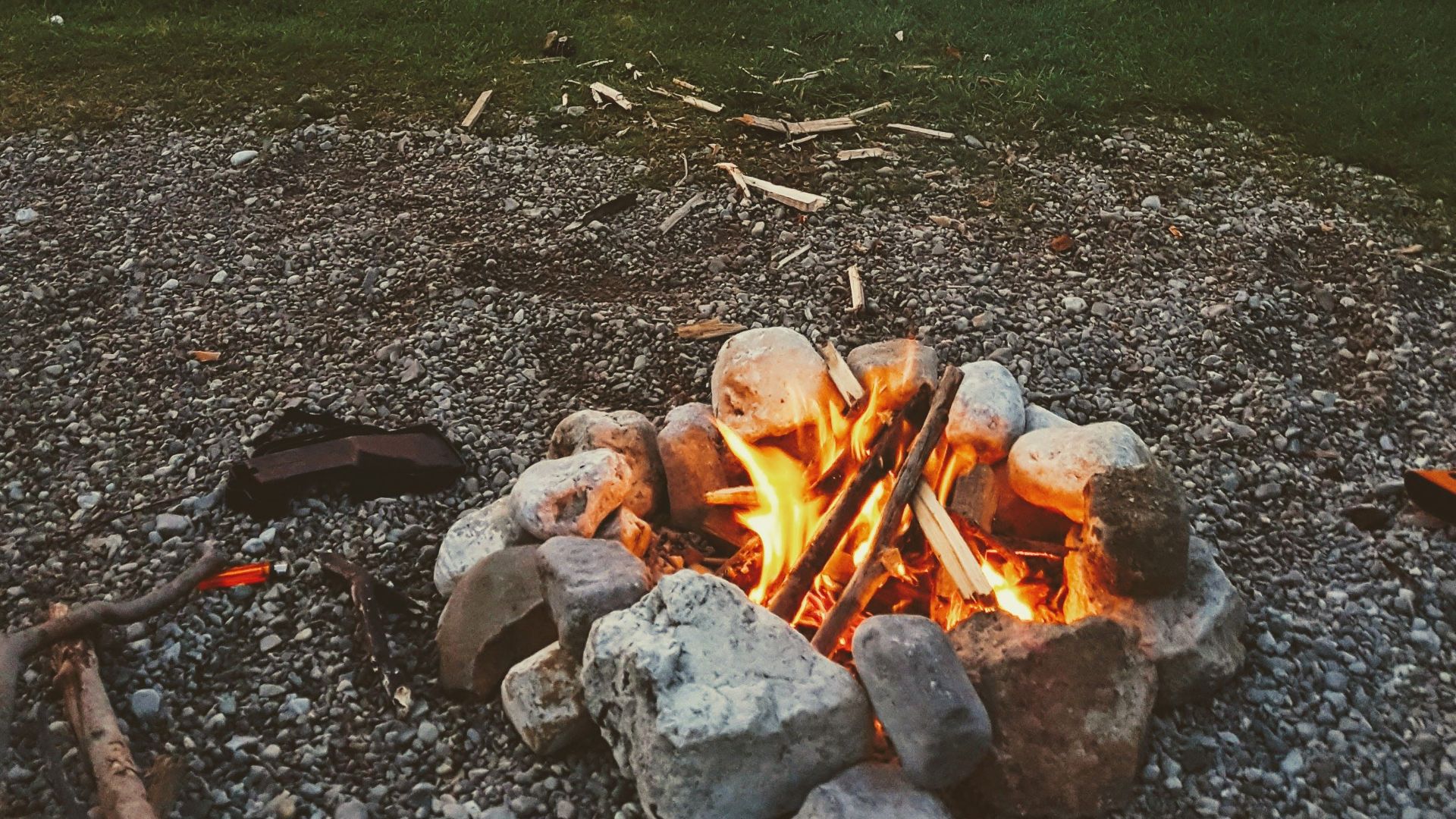 A peaceful campfire by the lake with beautiful sunset tones reflecting on the water.