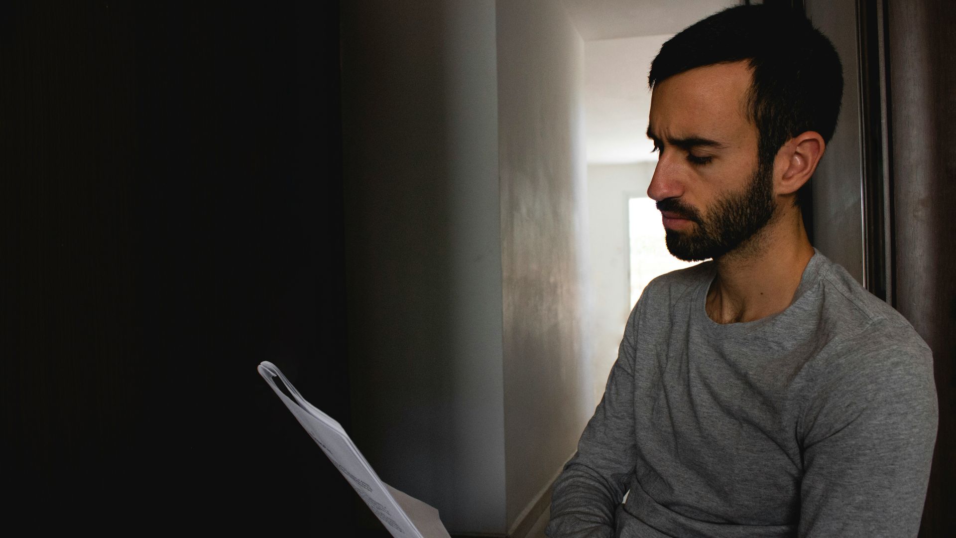 man in gray crew neck shirt holding white printer paper