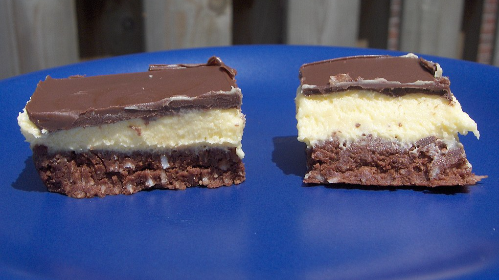 Close Up Photo of Two nanaimo bars on a blue plate.