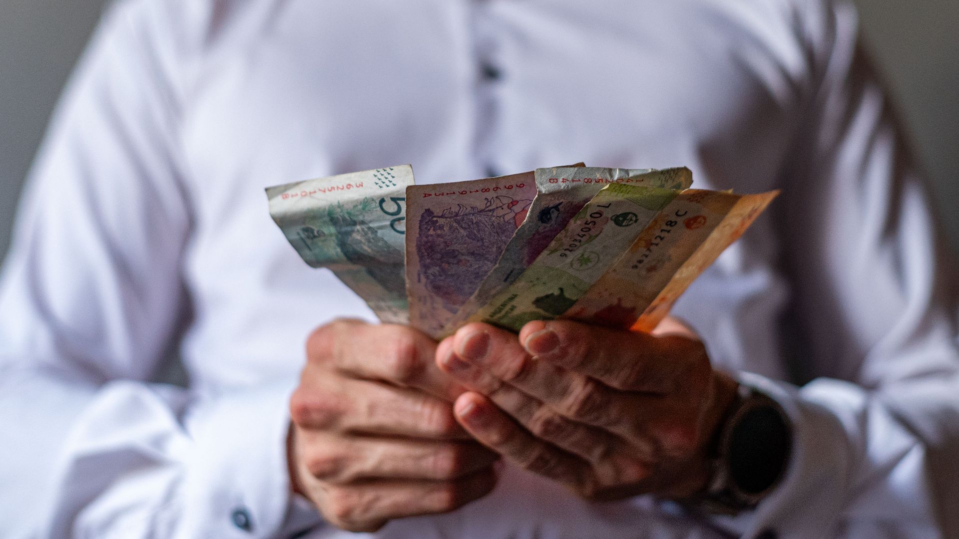 Man holding Argentine Peso banknotes in Buenos Aires, Argentina, illustrating currency concept.