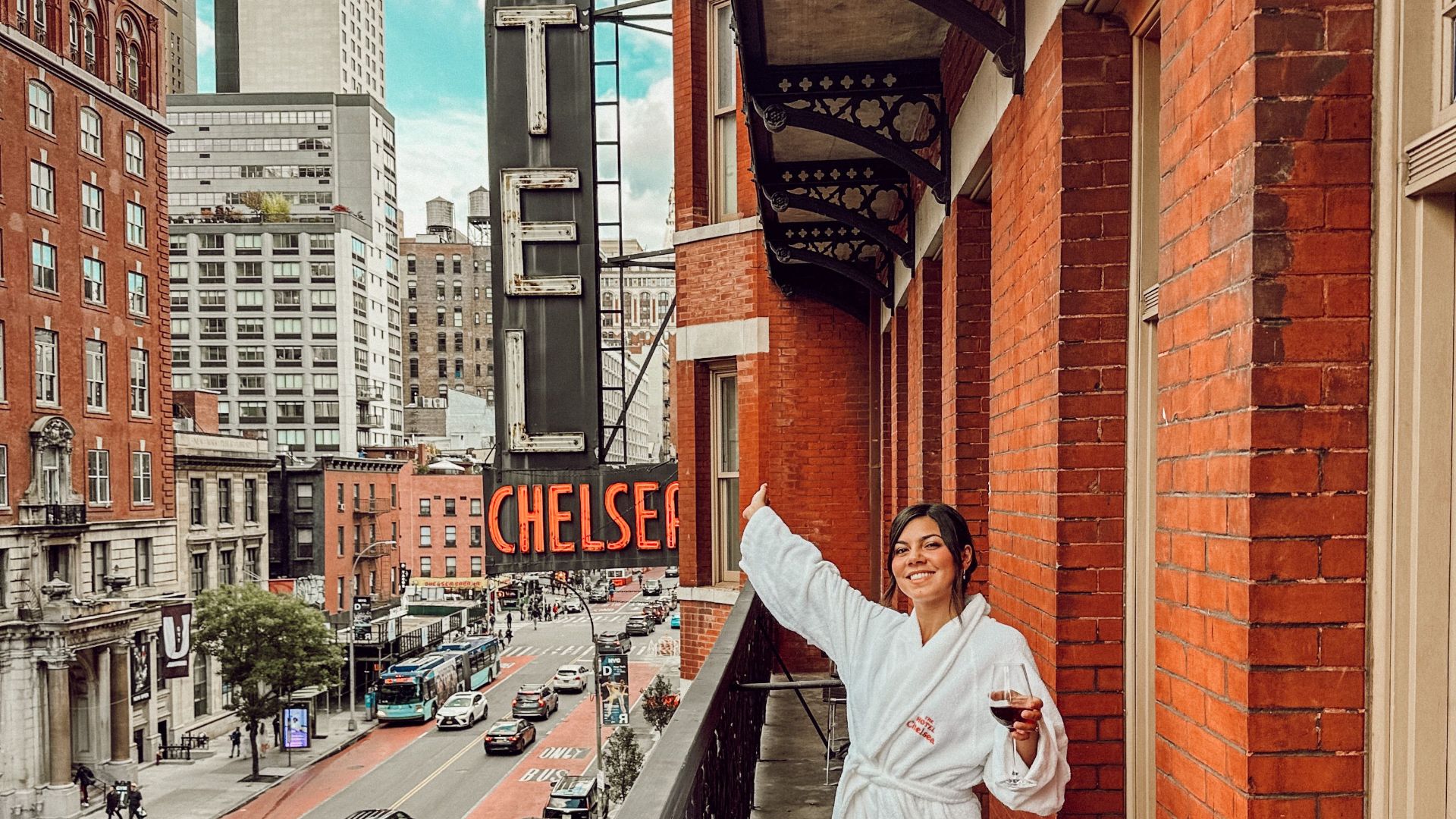 Woman in a bathrobe enjoying the view from a Hotel Chelsea balcony in New York City.